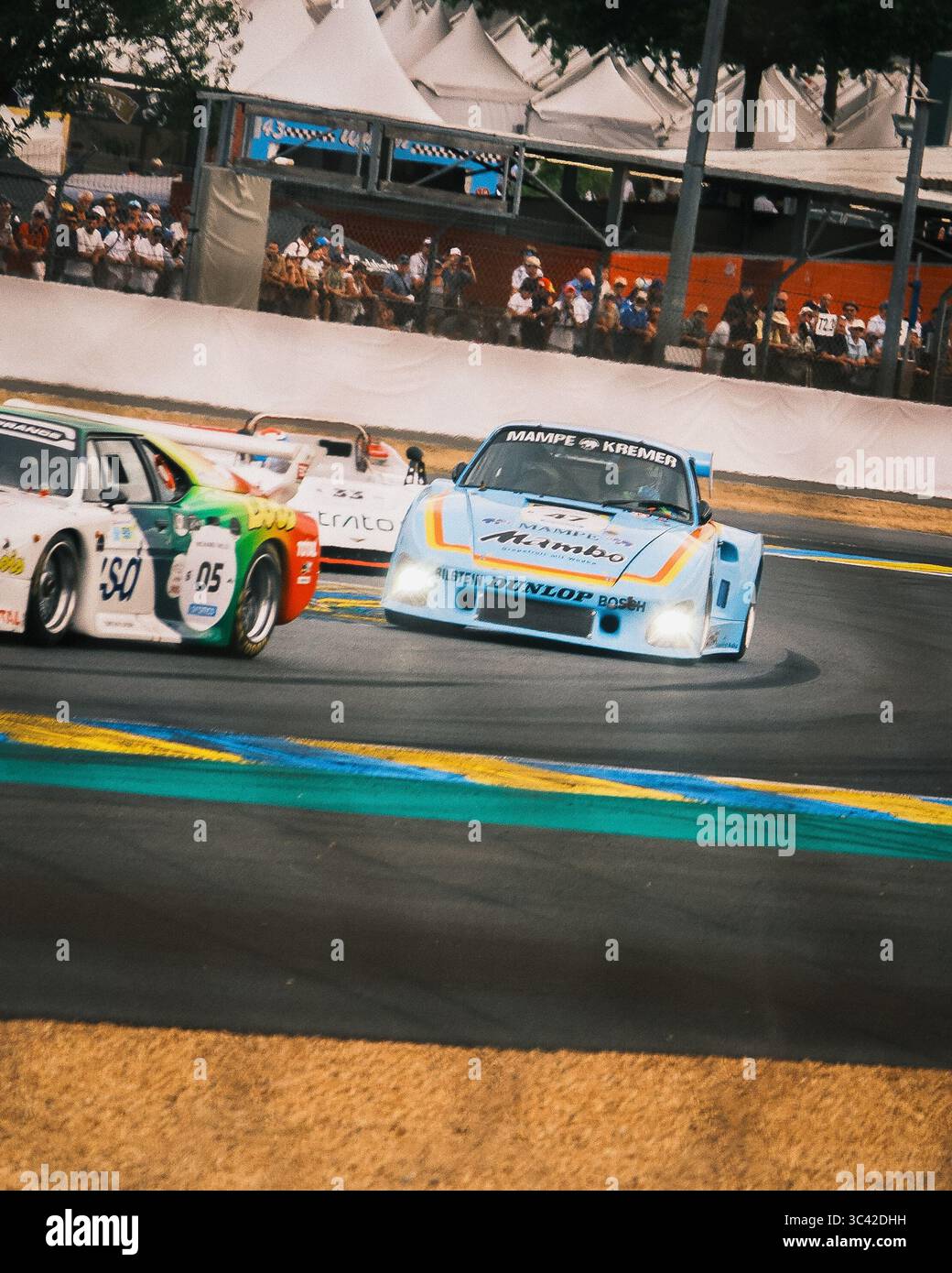 Le Mans, Francia - 07 giugno 2025: Vista delle eleganti auto da corsa che corrono intorno all'iconica pista Place Luigi Chinetti, i loro colori vivaci creano una sfocatura contro l'asfalto e la folla. Foto Stock