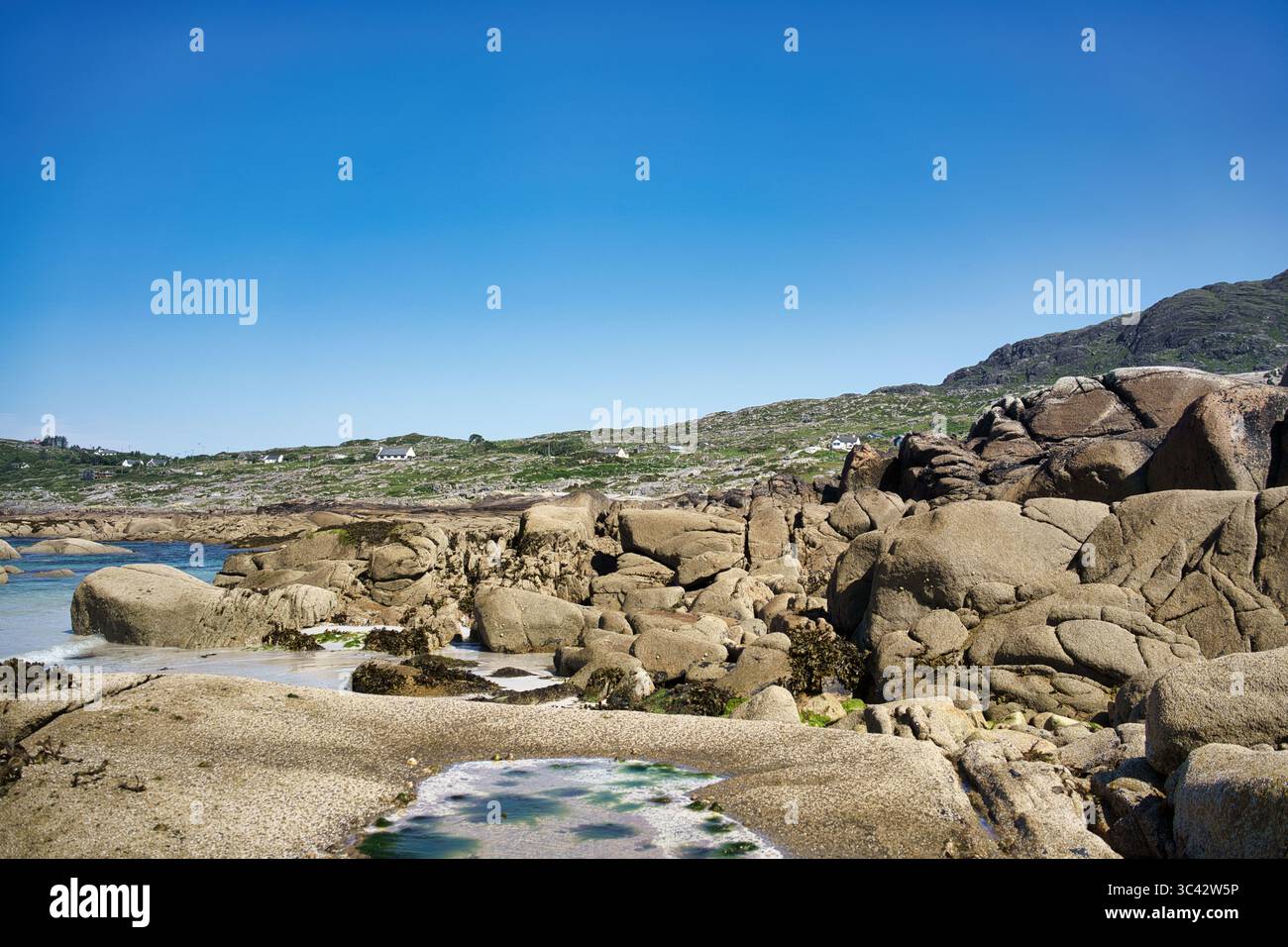 Un paesaggio costiero panoramico in Irlanda, con un cielo azzurro, formazioni rocciose e un'atmosfera serena. Foto Stock