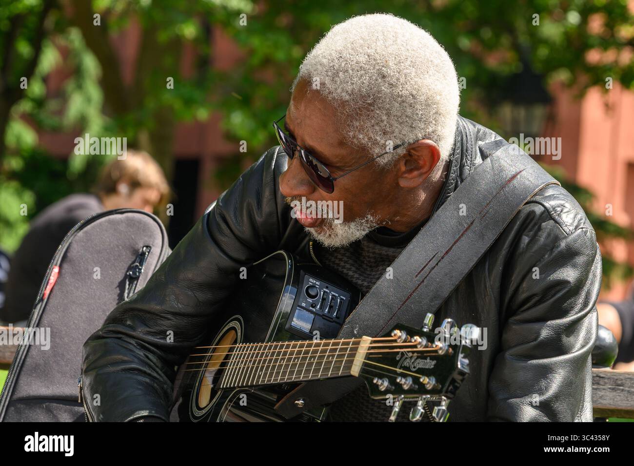 Un aviatore Ray-Ban che indossa Musical Street Performer con chitarra Takamine a Washington Square Park, Greenwich Village, New York, USA. Foto Stock
