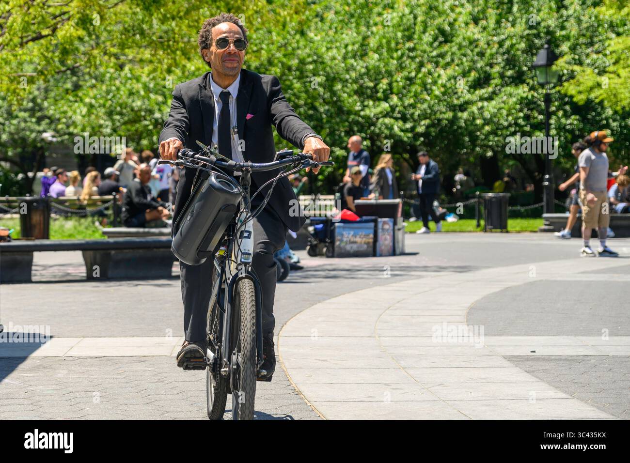 Un uomo felice, eccentrico e adatto ascolta il suo Boombox mentre gira in bicicletta attraverso Washington Square Park, New York. Foto Stock Un uomo felice, eccentrico e adatto ascolta il suo Boombox mentre gira in bicicletta attraverso Washington Square Park, New York. Foto Stock