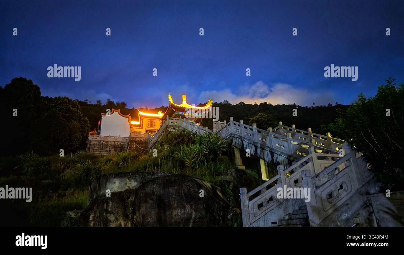 La scena fotografica mozzafiato al tramonto si svolge alle grotte di Batu in Malesia, dove un cielo d'ora d'oro incontra le luci della torre urbana e l'illuminazione notturna della strada. Da - Immagine stock catturata con smartphone