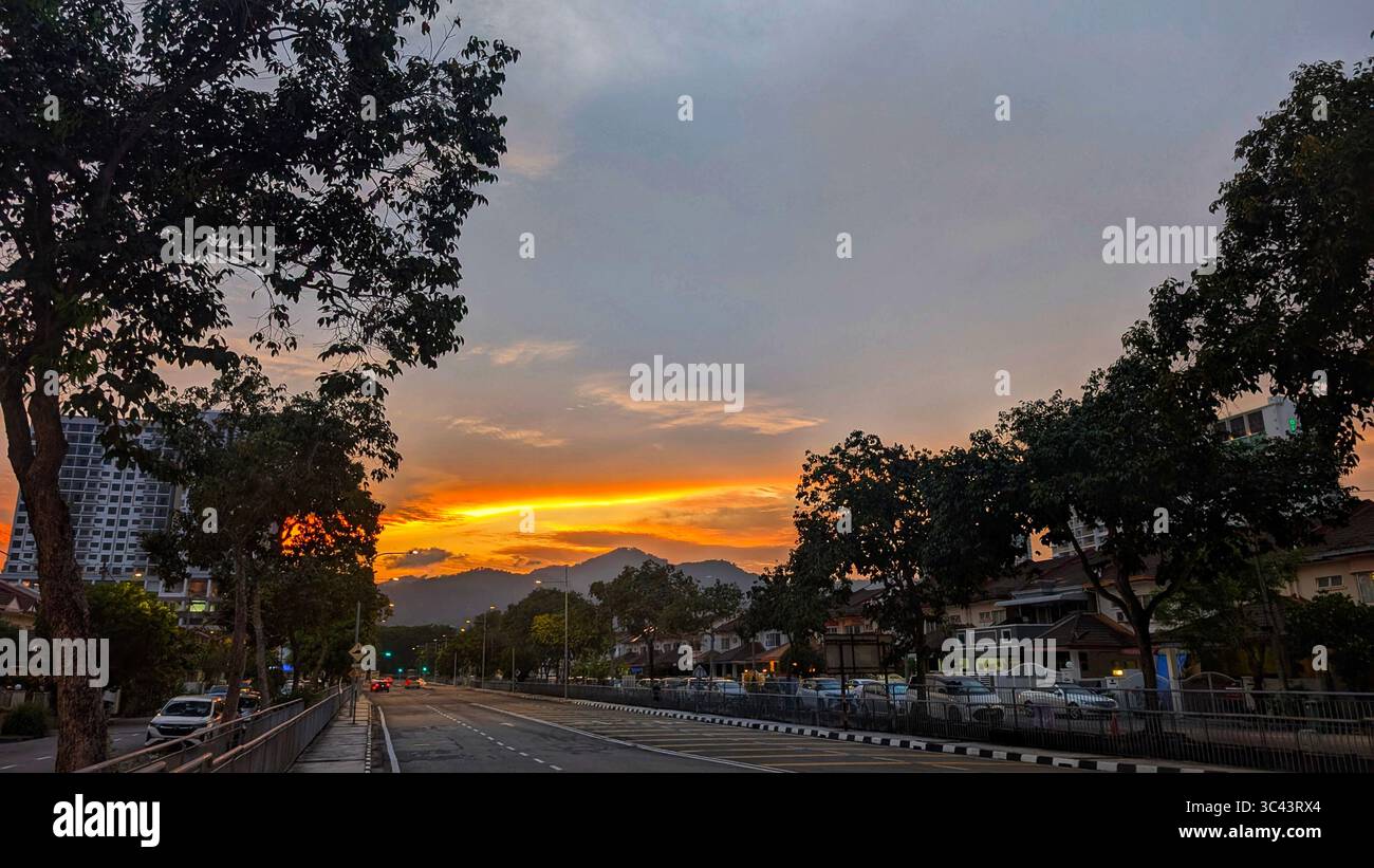 La scena fotografica mozzafiato al tramonto si svolge alle grotte di Batu in Malesia, dove un cielo d'ora d'oro incontra le luci della torre urbana e l'illuminazione notturna della strada. Da - Immagine stock catturata con smartphone