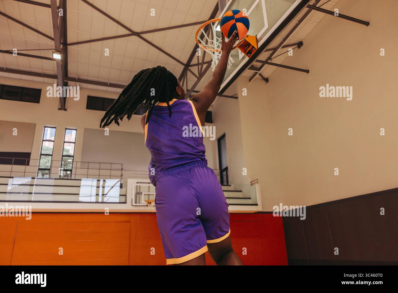 Atleta di pallacanestro in una palestra indoor professionale. La scena enfatizza le capacità fisiche, la precisione e la de dell'atleta Foto Stock