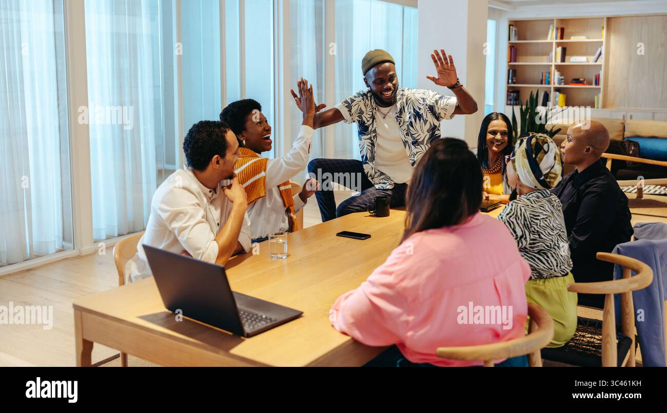 Un gruppo di colleghi diversi in un ufficio esprime entusiasmo e cameratismo mentre festeggiano un successo con un massimo di cinque persone. Lavoro di squadra, collaborazione Foto Stock