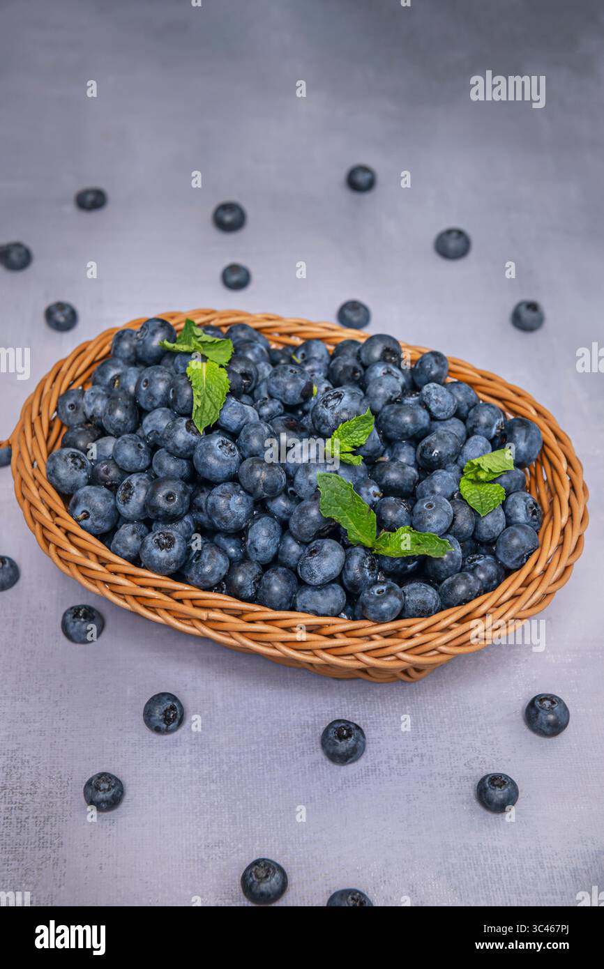 Cesto appeso pieno di mirtilli, fotografato all'aperto su sfondo naturale per uno stile fresco e organico Foto Stock