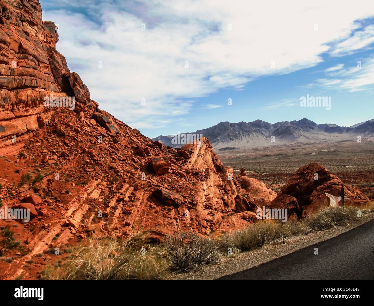 Vista sulla Valle del fuoco, Nevada, USA, con la sua iconica pietra arenaria rossa in primo piano e le vette frastagliate delle montagne North Muddy nella ba Foto Stock