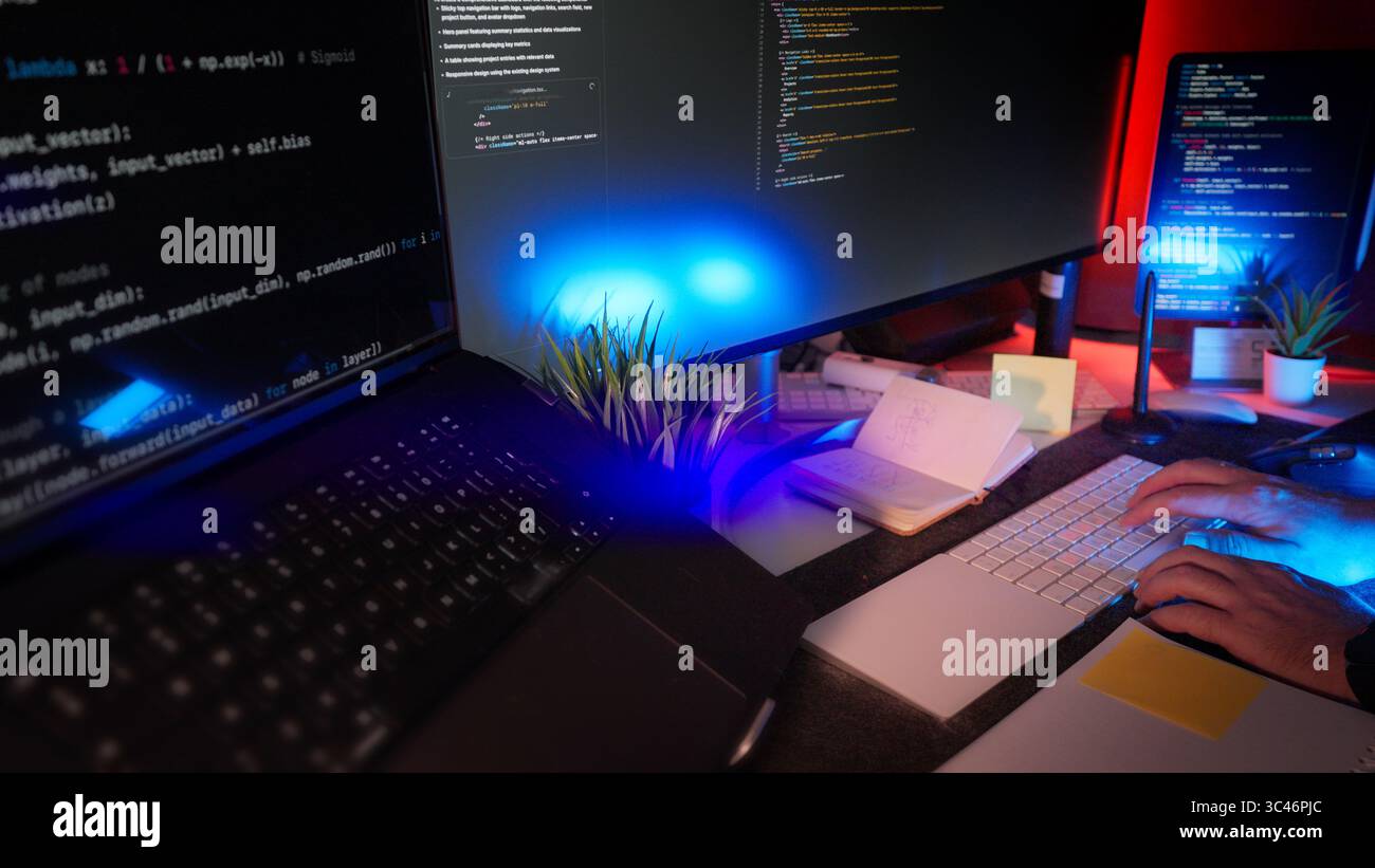 Programmatore che scrive codice spazio di lavoro notturno remoto con più schermi, illuminazione RGB e scrivania moderna organizzata. Concetto di creazione digitale, software de Foto Stock