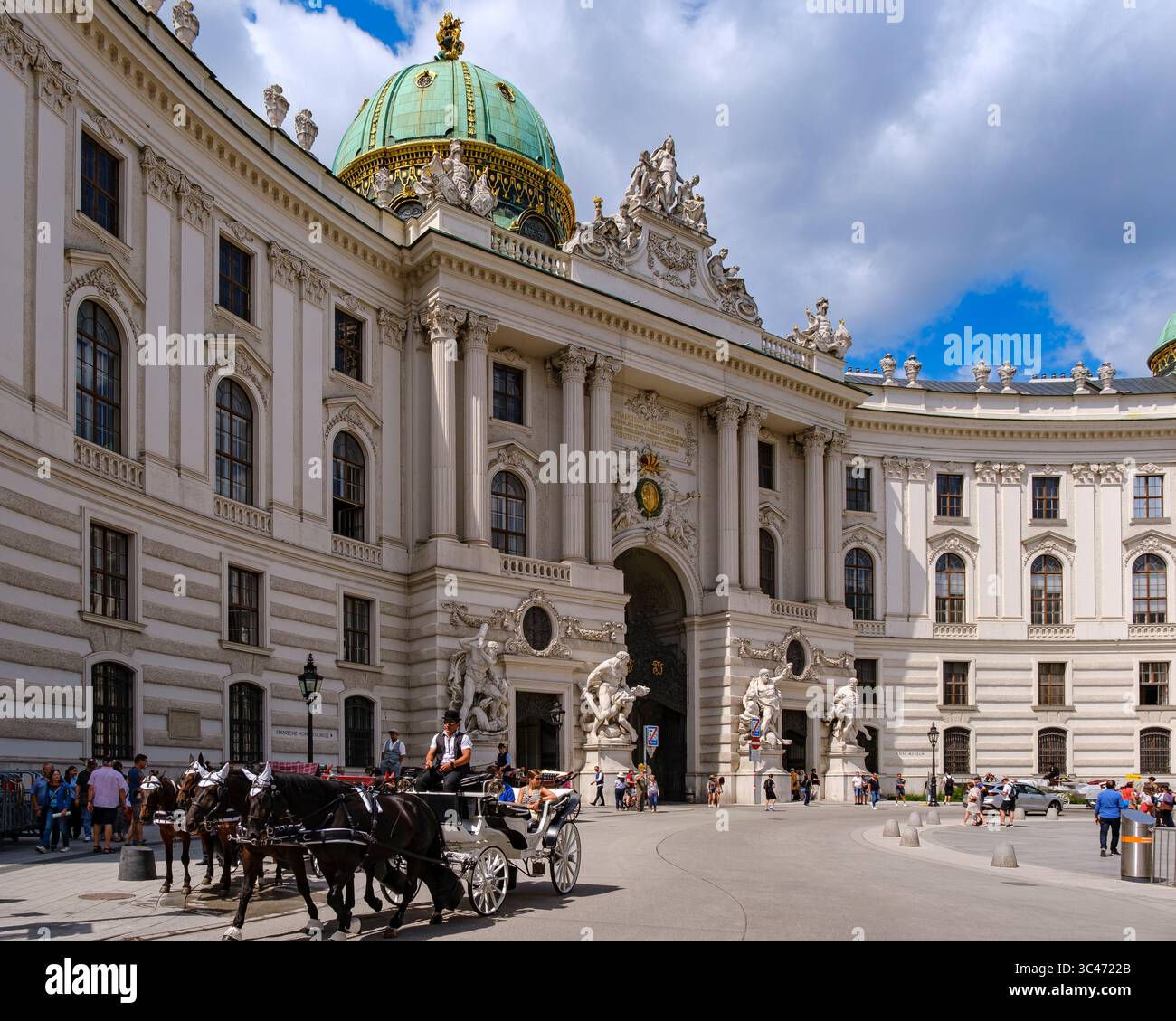 Scena quotidiana piena di turisti e carrozze trainate da cavalli su Michaelerplatz di fronte all'ala Michaelertrakt dell'Hofburg di Vienna, Vienna, Austria. Foto Stock