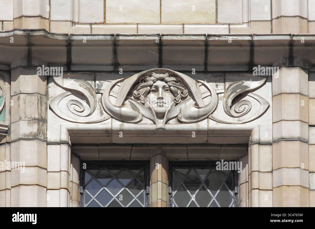 Testa femminile inserita in un vorticoso design Art Nouveau, sopra una finestra al secondo piano sulla facciata del pub Fox and Anchor, Chaterhouse St, Londra. Foto Stock