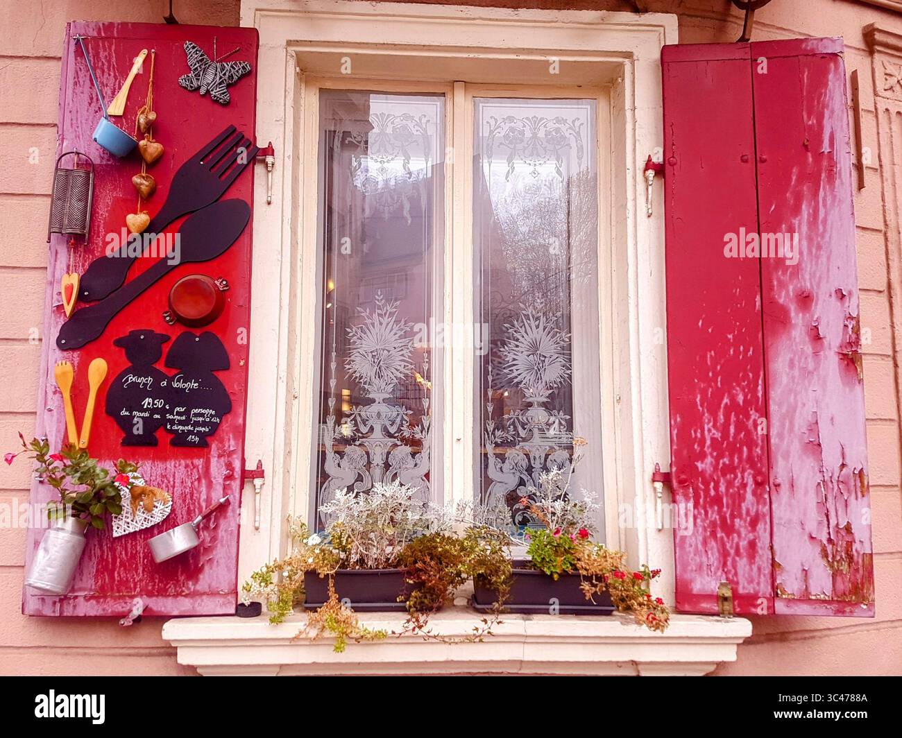 Tipica finestra alsaziana con persiane rosse e decorazioni di utensili da cucina in affascinante stile francese Foto Stock