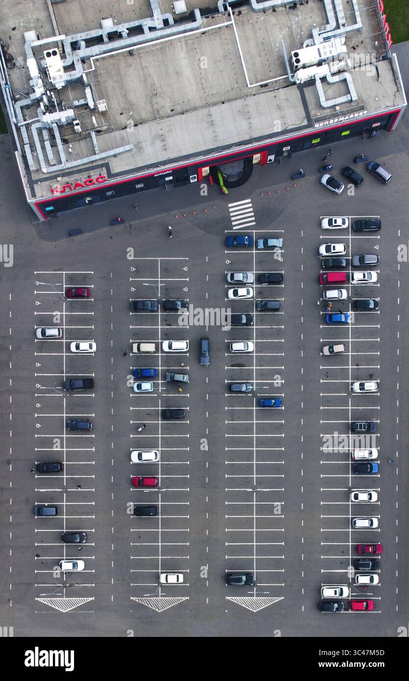 Charkiv, Ucraina - 06 giugno 2021: Veduta aerea di un supermercato con il suo parcheggio pieno di auto, che getta ombre sull'asfalto grigio. Foto Stock