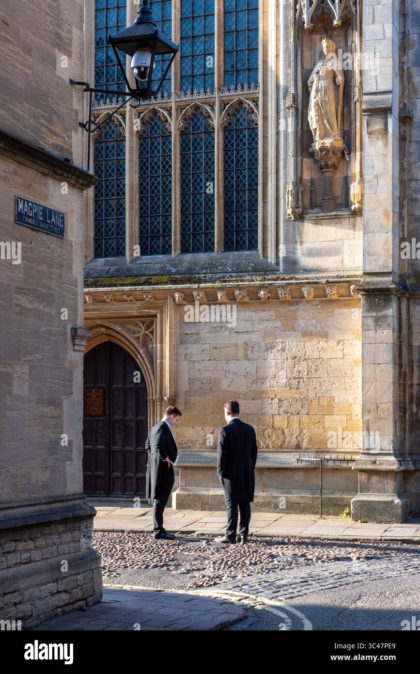 Due studenti sulla via del ritorno da un ballo estivo del college fanno una pausa per chiacchierare al mattino presto, Merton Street, Oxford, Regno Unito Foto Stock