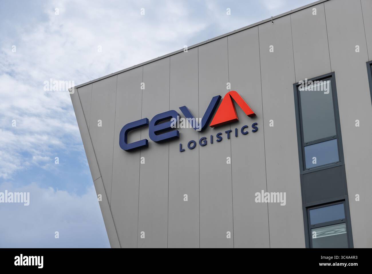 Il logo "CEVA LOGISTICS", con testo blu e una suggestiva "A" e uno chevron rosso, è montato sull'elegante facciata grigia di un edificio moderno contro un bricco Foto Stock