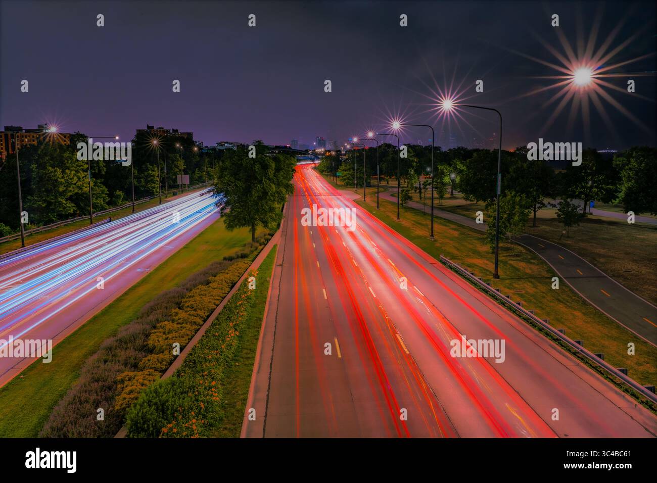 Le strisce di traffico notturno lungo Lake Shore Drive di Chicago creano vivaci sentieri leggeri. Lo skyline della città segna l'orizzonte, sottolineando l'atmosfera Foto Stock