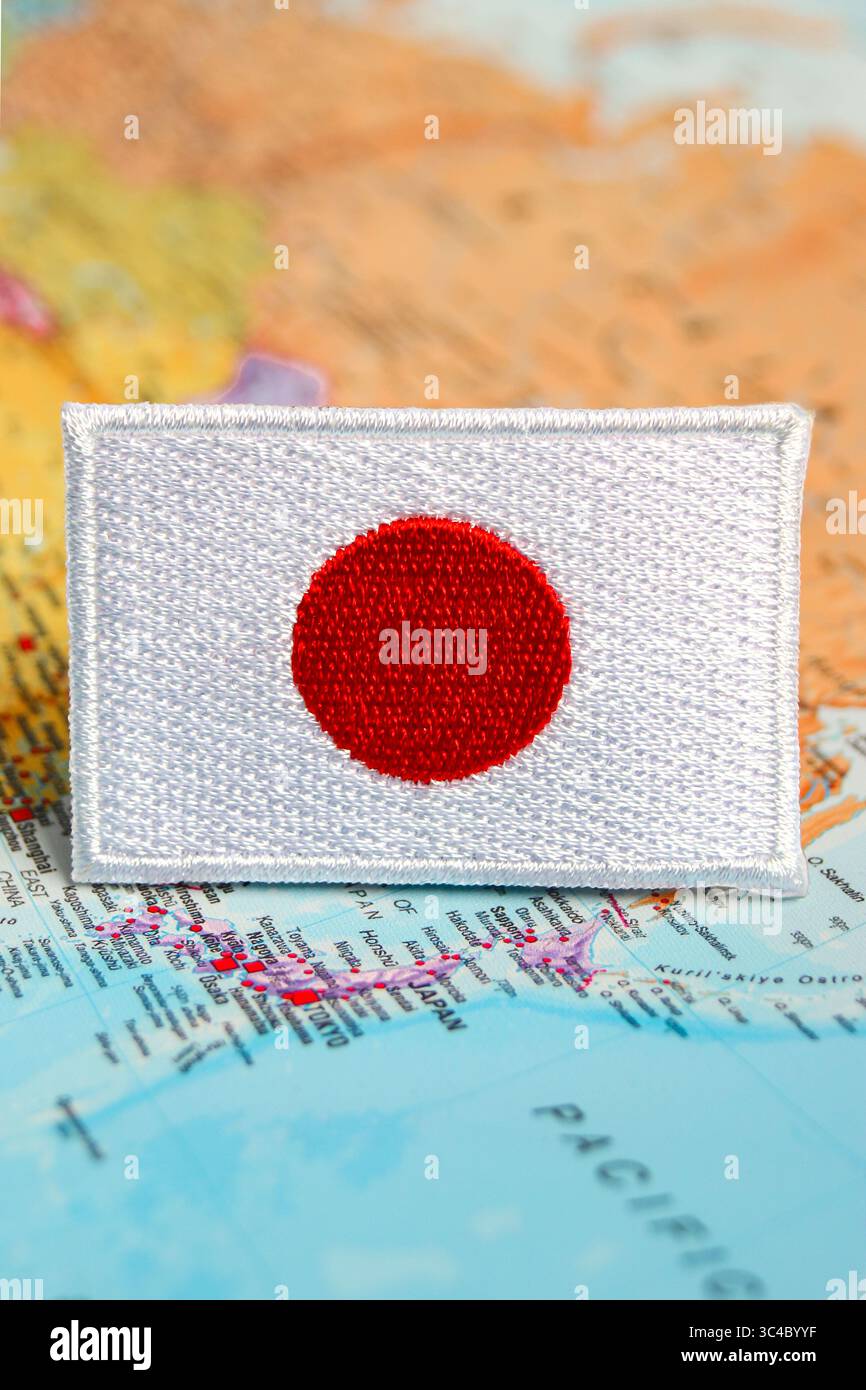 Toppa con bandiera del Giappone ricamata e ecocompatibile posizionata sulla mappa del mondo del Giappone. Ideale per turismo ecologico, viaggi consapevoli e temi di sensibilizzazione globale. Foto Stock