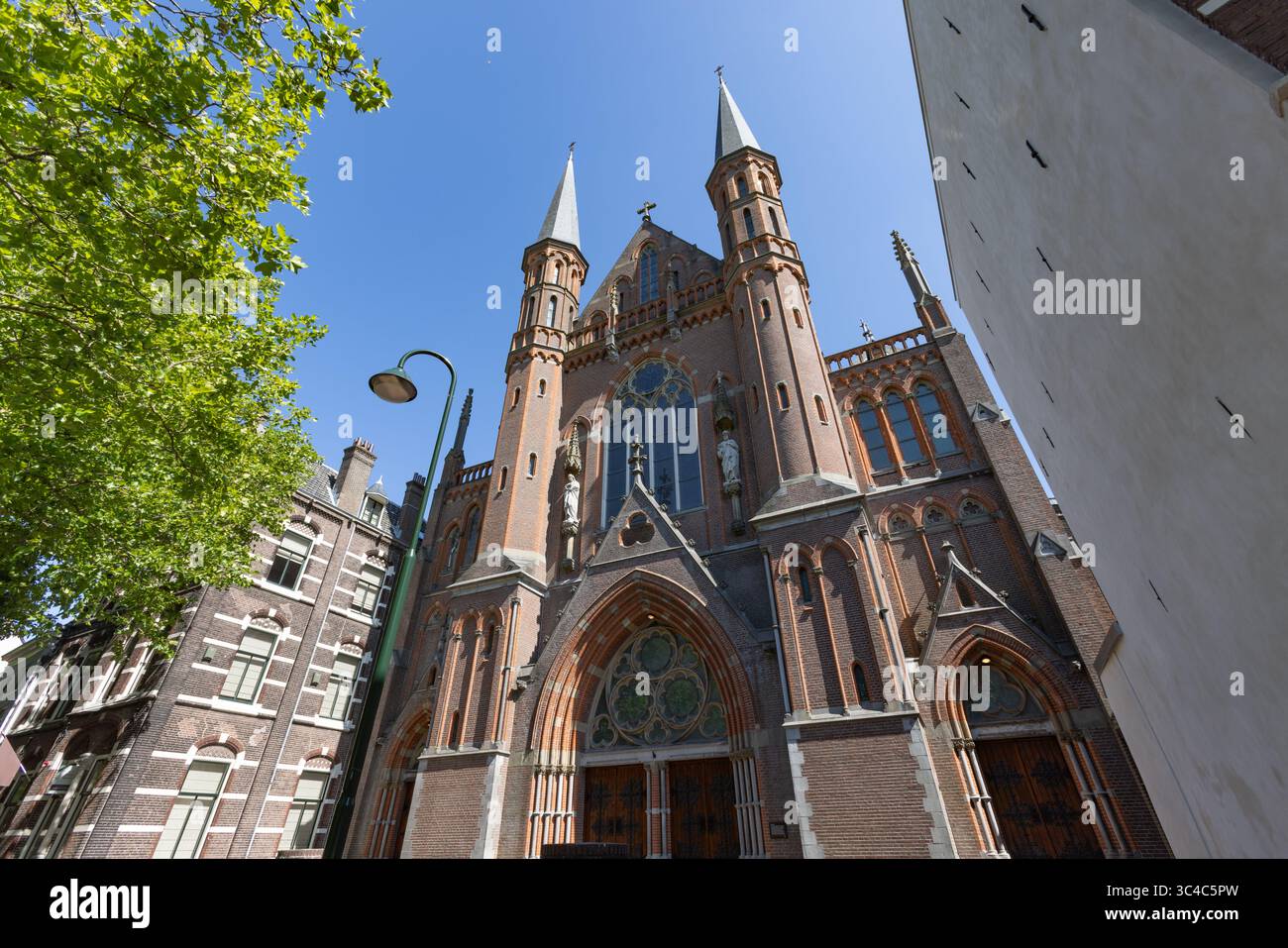 Una grandiosa chiesa in mattoni rossi 'De Gouwekerk' con due torreggianti guglie e un'architettura neogotica ornata si erge maestosamente su un blu brillante Foto Stock