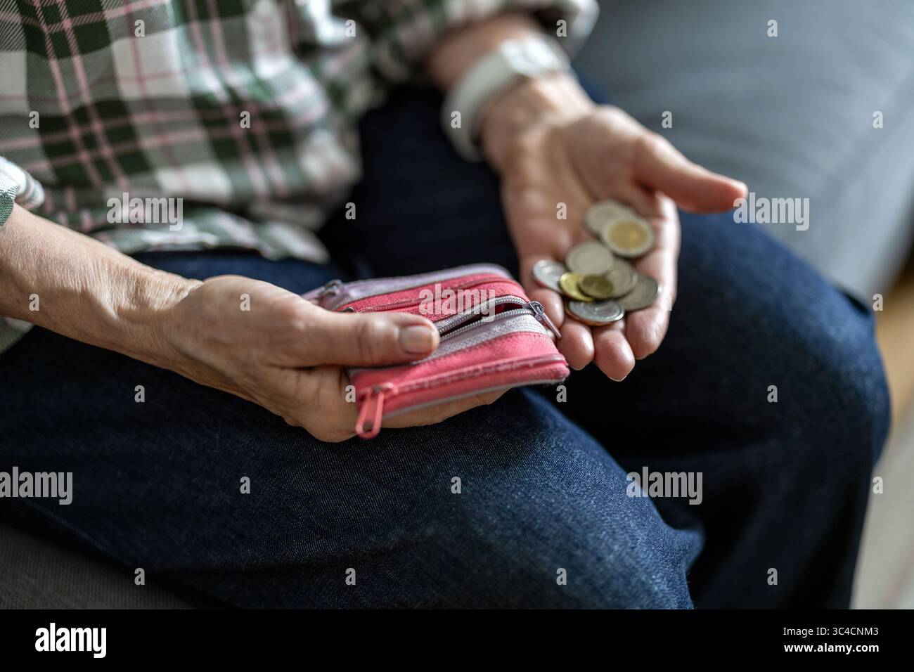 Primo piano delle mani di una donna anziana che tiene una moneta Foto Stock