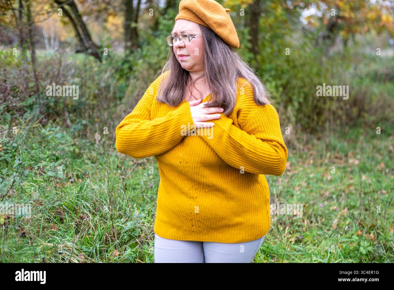 Donna di mezza età frizioni torace, dolore cardiaco colpisce inaspettatamente, espressione preoccupata, crisi di salute, momento emotivo, rara condizione cardiaca, salute Foto Stock