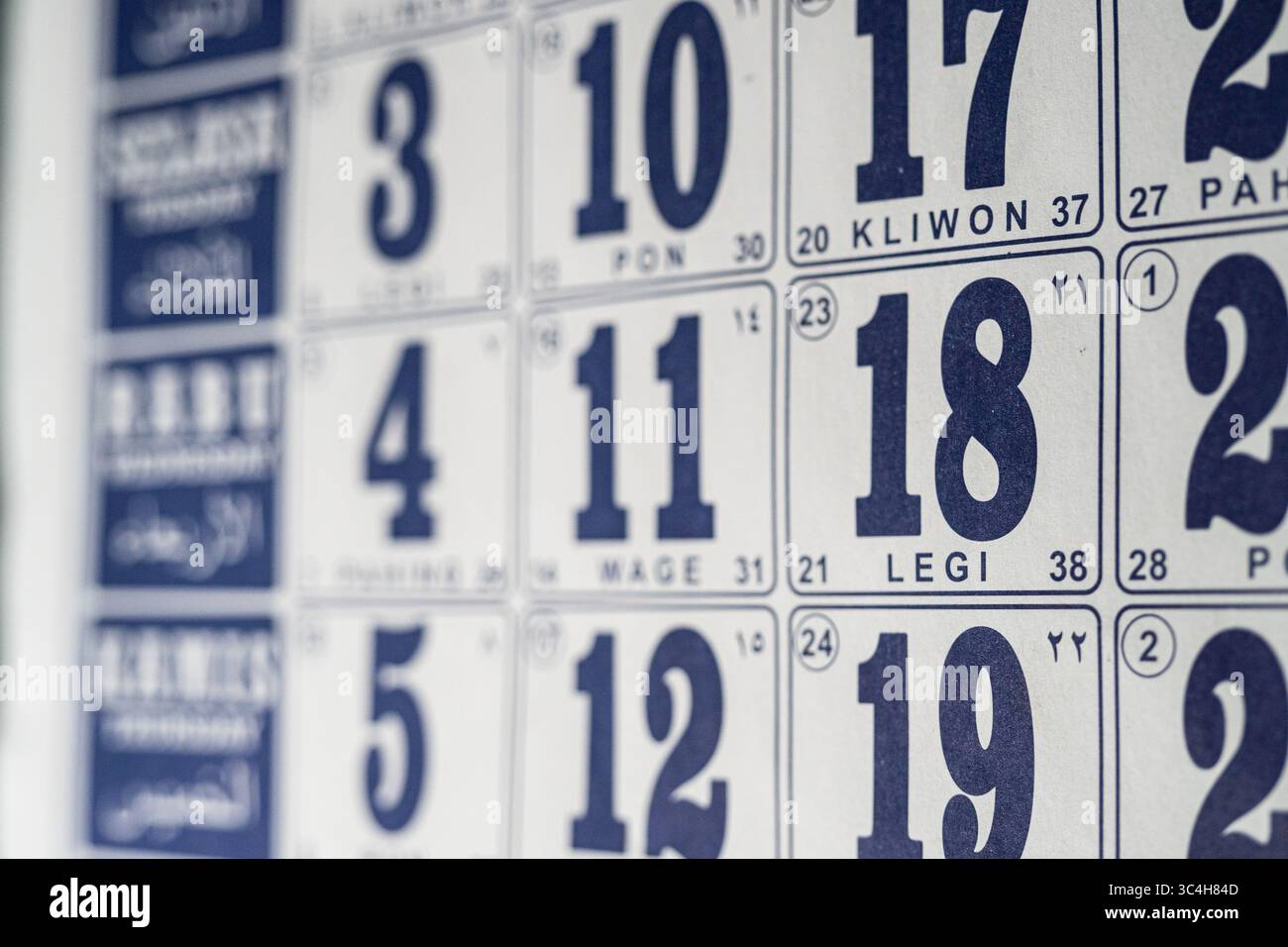 Foto macro ad angolo laterale di un calendario da parete, con particolare attenzione a una data specifica. Ideale per blog, grafica per la gestione del tempo, layout editoriali o pianificazione Foto Stock