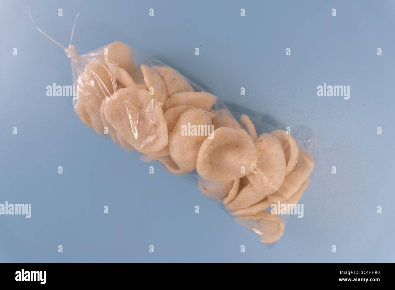 Un sacchetto di plastica sigillato di cracker tradizionali (kerupuk) legato nella parte superiore. Ideale per confezioni di alimenti, promozioni di snack locali o blog culinario Ill Foto Stock