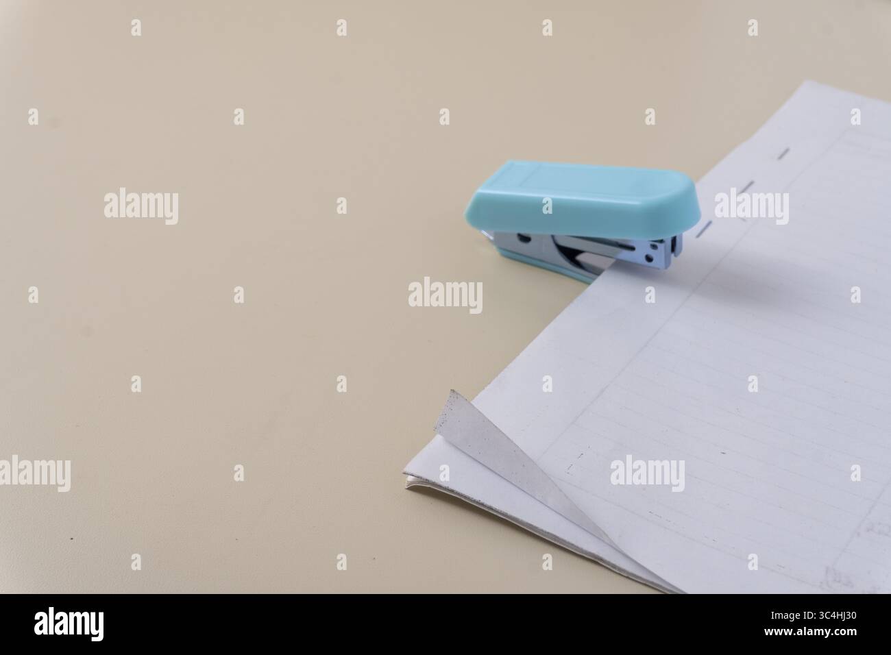 Una cucitrice in azione ritaglio di una risma di carta catturata in primo piano. Il momento della routine d'ufficio, con la cucitrice che si preme verso il basso, sistemate in modo ordinato Foto Stock