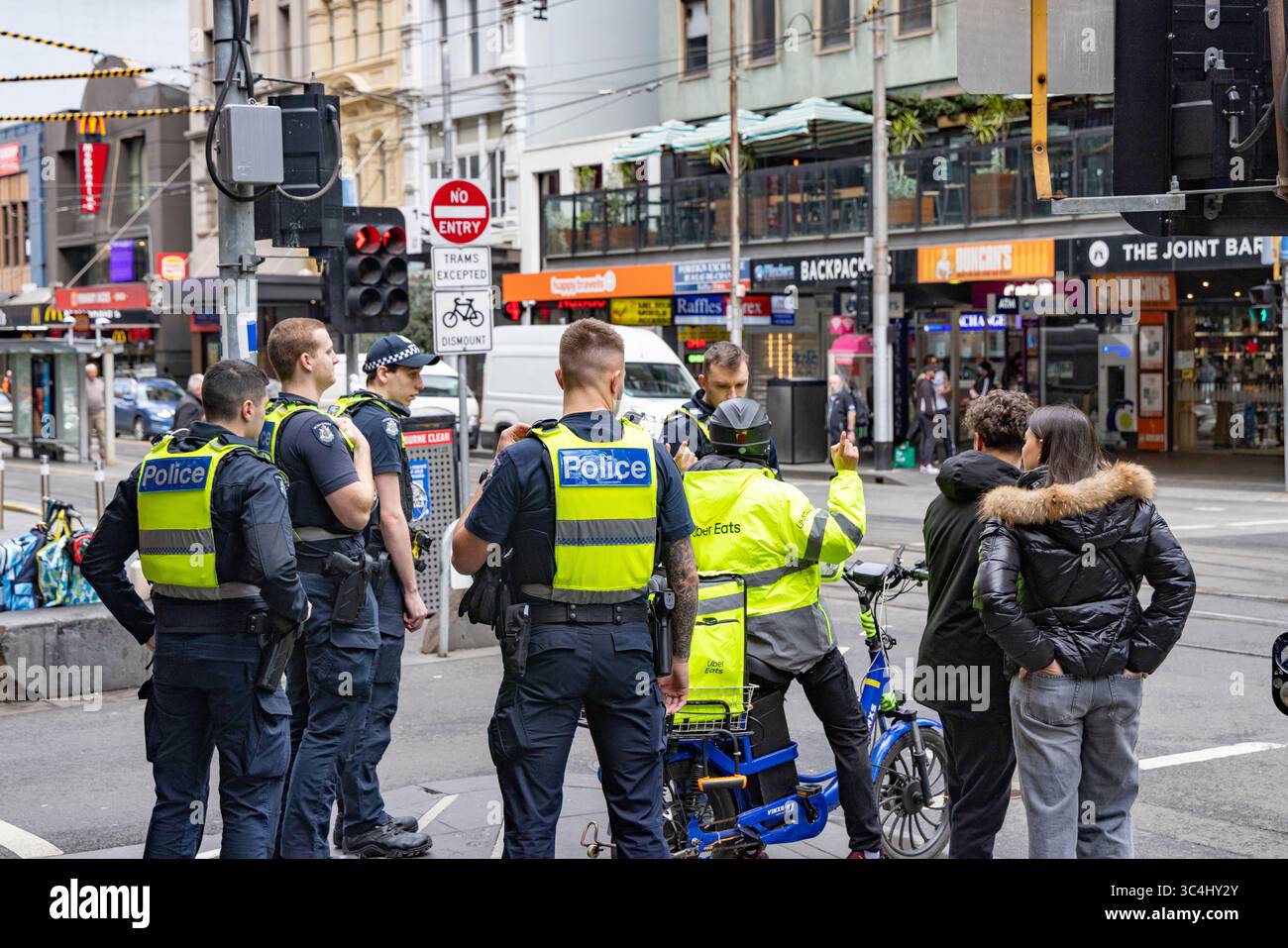 Melbourne, Victoria, Australia, un gruppo di agenti armati di polizia avvisano un Uber che mangia ciclisti su una violazione del traffico su Elizabeth Street Foto Stock