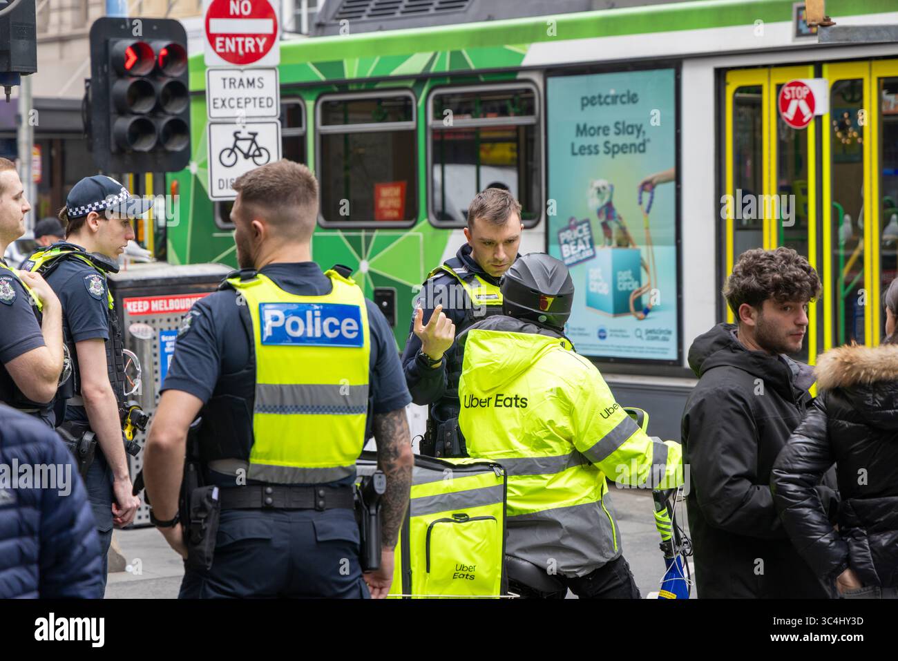 Melbourne, Victoria, Australia, un gruppo di agenti armati di polizia avvisano un Uber che mangia ciclisti su una violazione del traffico su Elizabeth Street Foto Stock