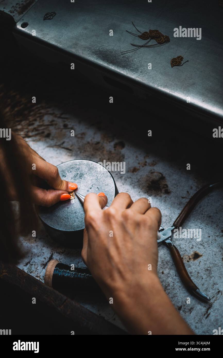 Gioielli in metallo per lucidare le mani artigianali femminili su mola in officina tradizionale. Abile artigiana, accessori fatti a mano, metallo portoghese Foto Stock