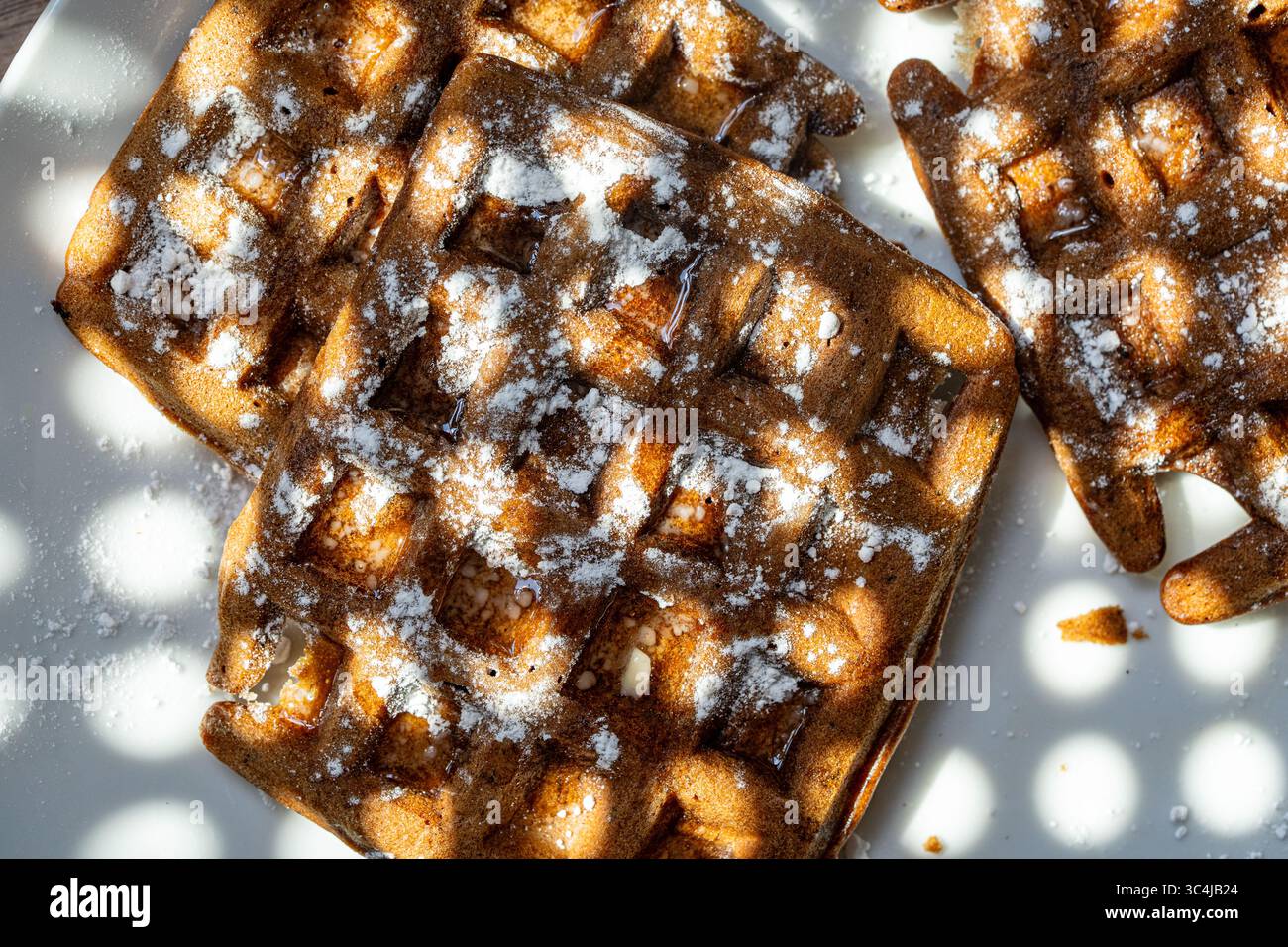 Cialde di pasta al cioccolato belga cosparse di zucchero a velo su sfondo bianco. Vista dall'alto. Primo piano. Foto di alta qualità Foto Stock