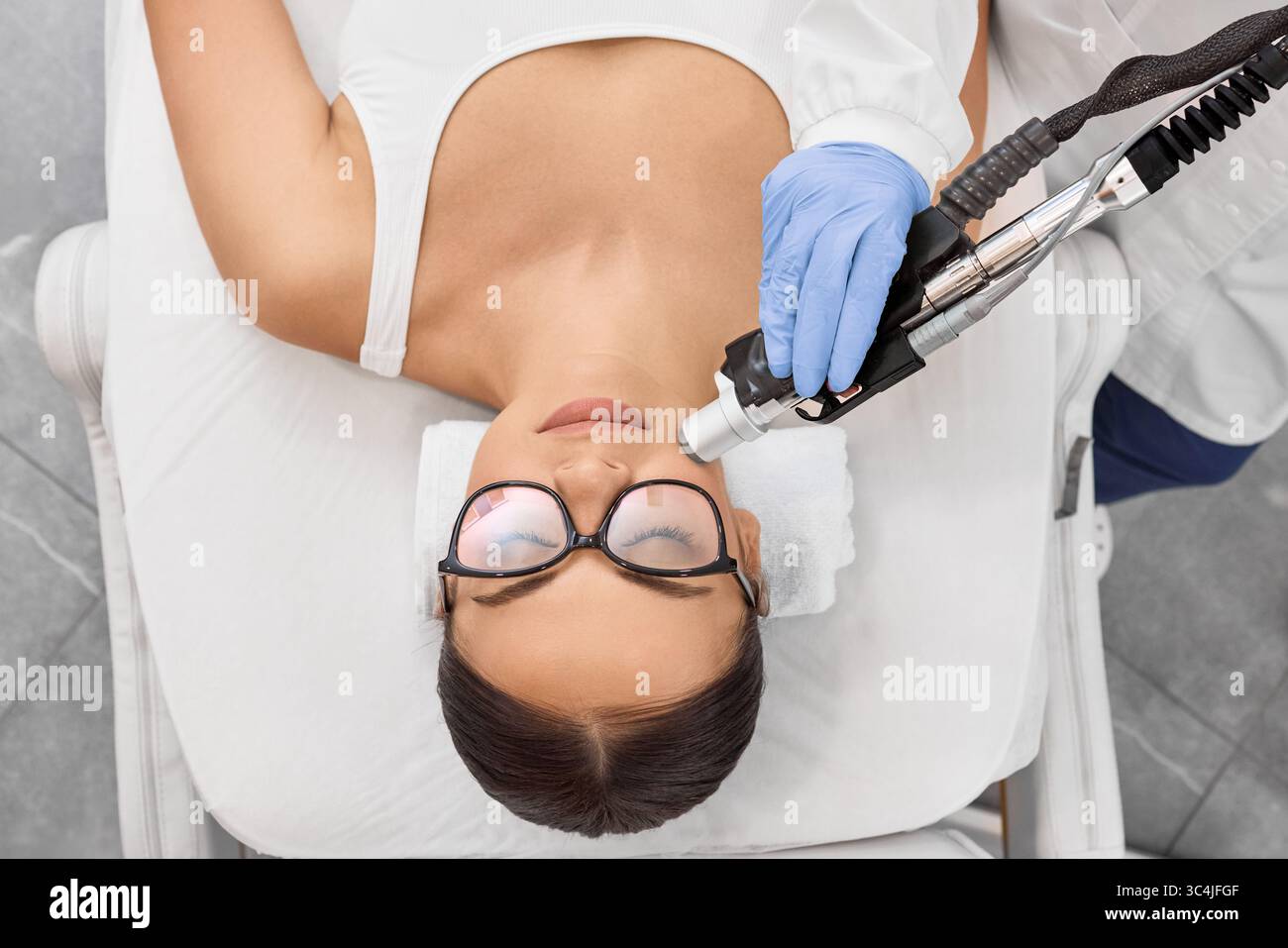 Bruna donna che ottiene la depilazione laser sul viso, l'epilazione laser sulle labbra, vista dall'alto. Rimozione dei peli del viso tramite laser Foto Stock