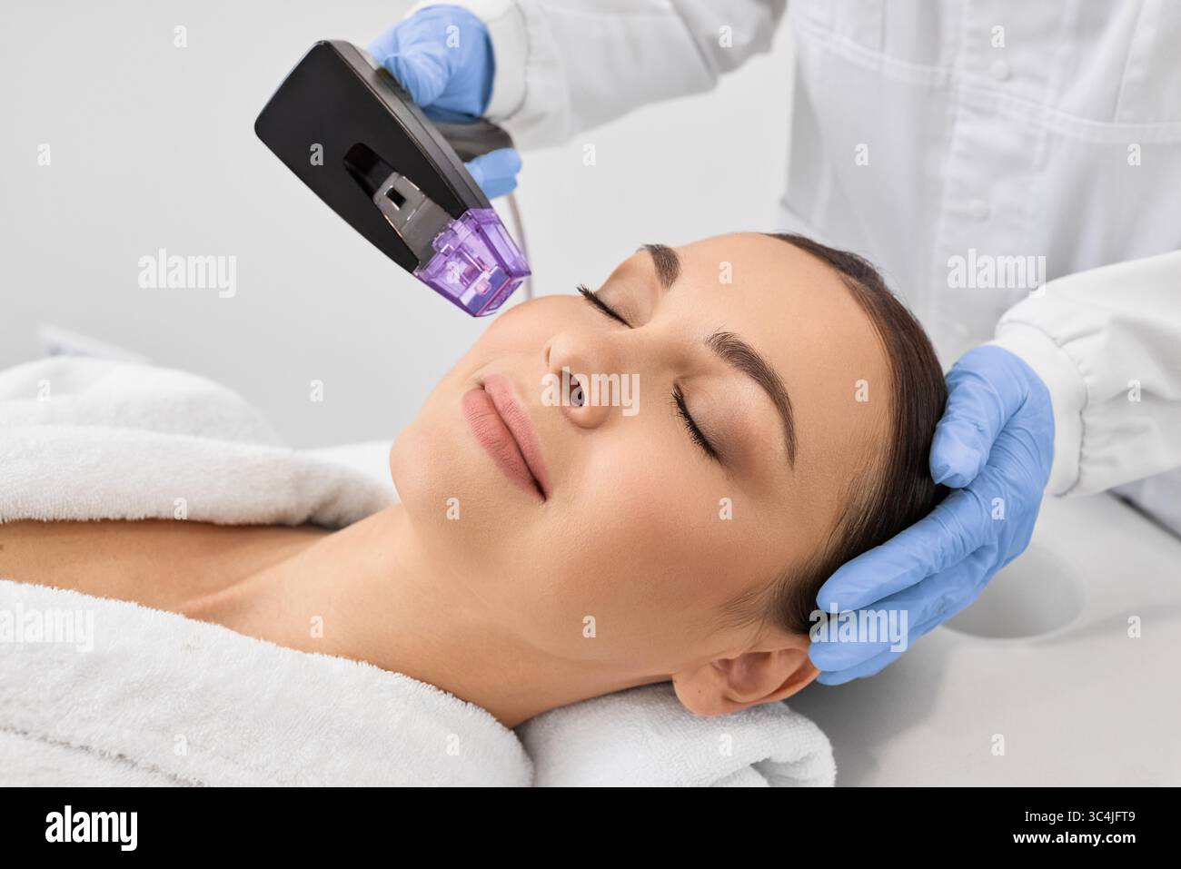 Sollevamento non chirurgico del viso della donna con l'aiuto di una nuova procedura di sollevamento a radiofrequenza microneedle. Procedura di sollevamento RF presso il salone di bellezza Foto Stock