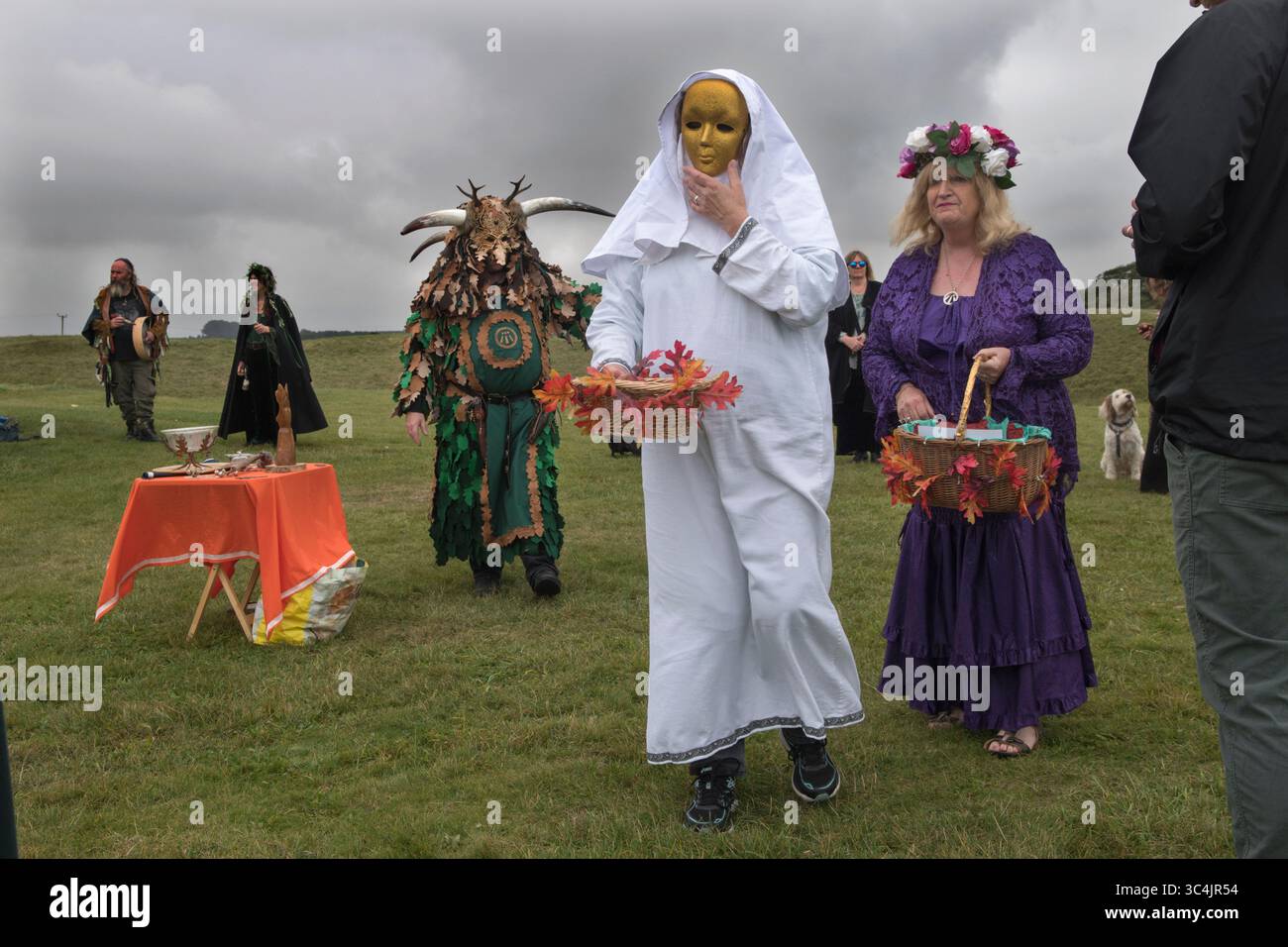 Dorset Druid Grove, Equinozio autunnale al monumento preistorico henge di Knowlton. Dennis Andrew propugna, il Dio Cornuto, noto anche come Cernunnos. Rita Andrew, come Nerthus, a volte conosciuta come la madre della Terra o Terra Mater. Dietro di lei c'è la fanciulla di Nerthus. Nelle tribù germaniche dell'età del ferro questo ruolo fu preso dai nemici catturati, dopo i loro ruoli rituali furono cerimonialmente bagnati, garrozzati e i loro corpi gettati nell'acqua. Dorset Inghilterra anni '2021 2020 UK HOMER SYKES Foto Stock