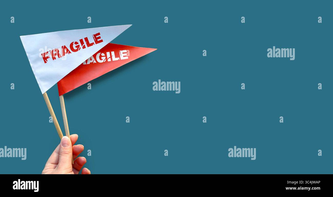 Bandiera in mano. Avvertenza "fragile". Confezioni, prodotti fragili. Sfondo blu. Copia spazio Foto Stock