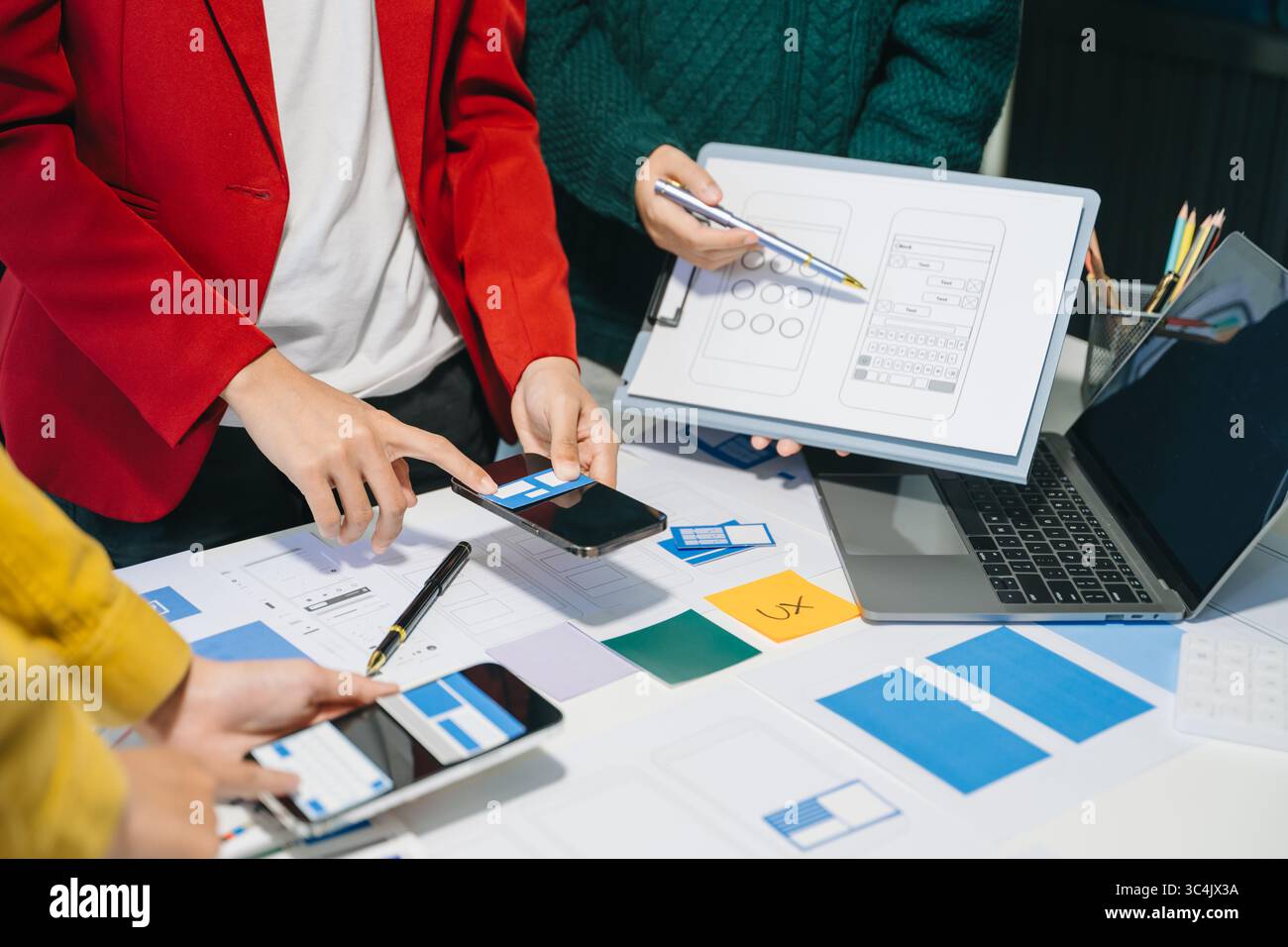 Sviluppatore UX e progettista dell'interfaccia utente che si occupa della progettazione di wireframe dell'interfaccia delle app mobili con il codice colore e la breif dei clienti negli uffici moderni. Foto Stock