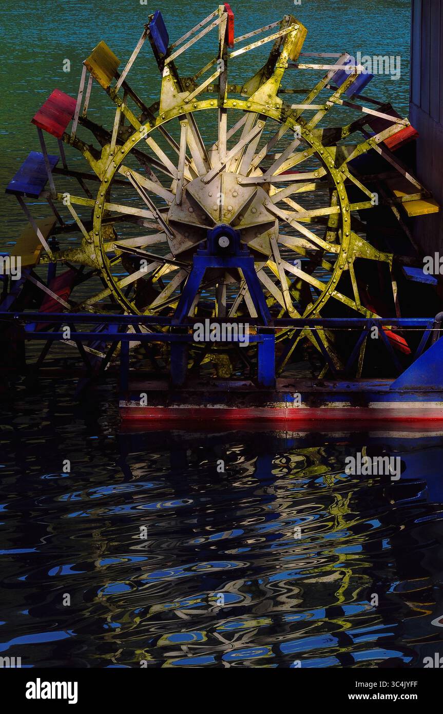 Ruota a pale gialla, rossa e blu di una nave d'epoca a poppa ormeggiata al massimo a na Soci nella regione del litorale, in Slovenia, per trasportare i turisti sulle acque verde smeraldo del bacino idrico Soci e del fiume Soca. Il lago è stato creato negli anni '1930 dalla costruzione di una diga idroelettrica. Il fiume Soca sorge nelle Alpi Giulie ed è noto come «la bellezza dello Smeraldo». Foto Stock