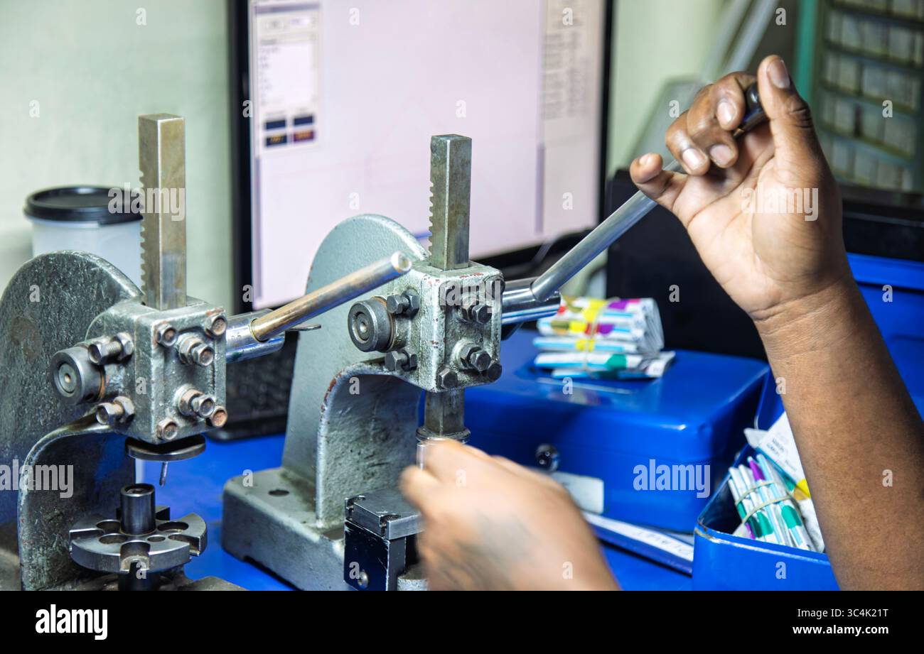 Presse manuali da officina, pressa a mandrino, in una fabbrica di lucidatura diamantata in Botswana, standard industriale, uomo africano che utilizza due utensili per premere meta Foto Stock