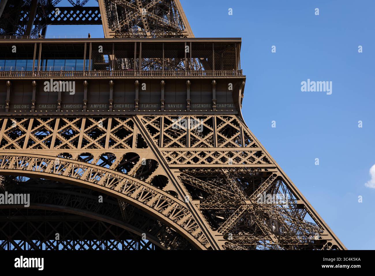 Primo piano dell'intricato reticolo della Torre Eiffel contro un cielo blu vibrante. L'immagine mostra i dettagli architettonici della torre e le decorazioni desi Foto Stock