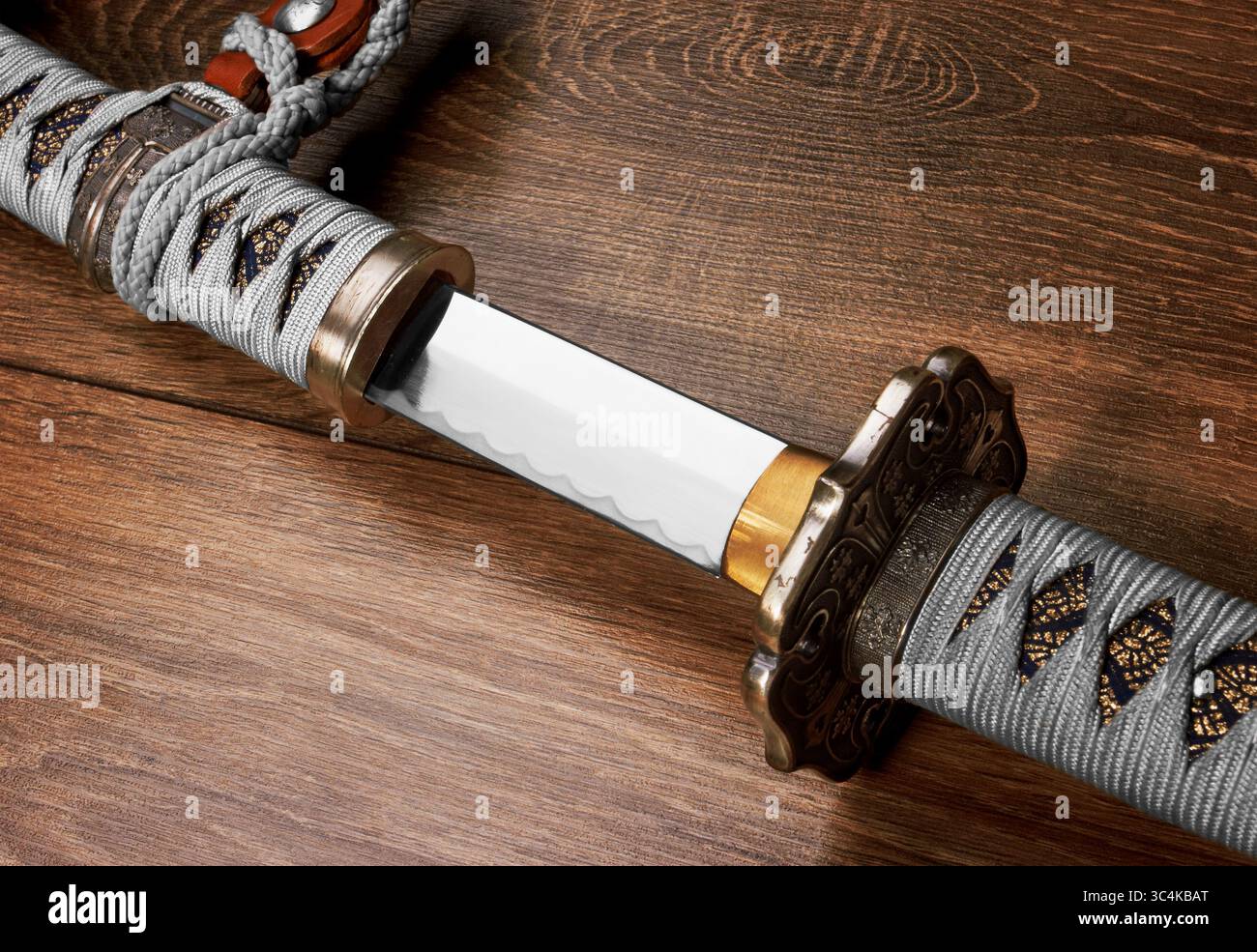 Katana, spada giapponese, su uno sfondo di legno Foto Stock