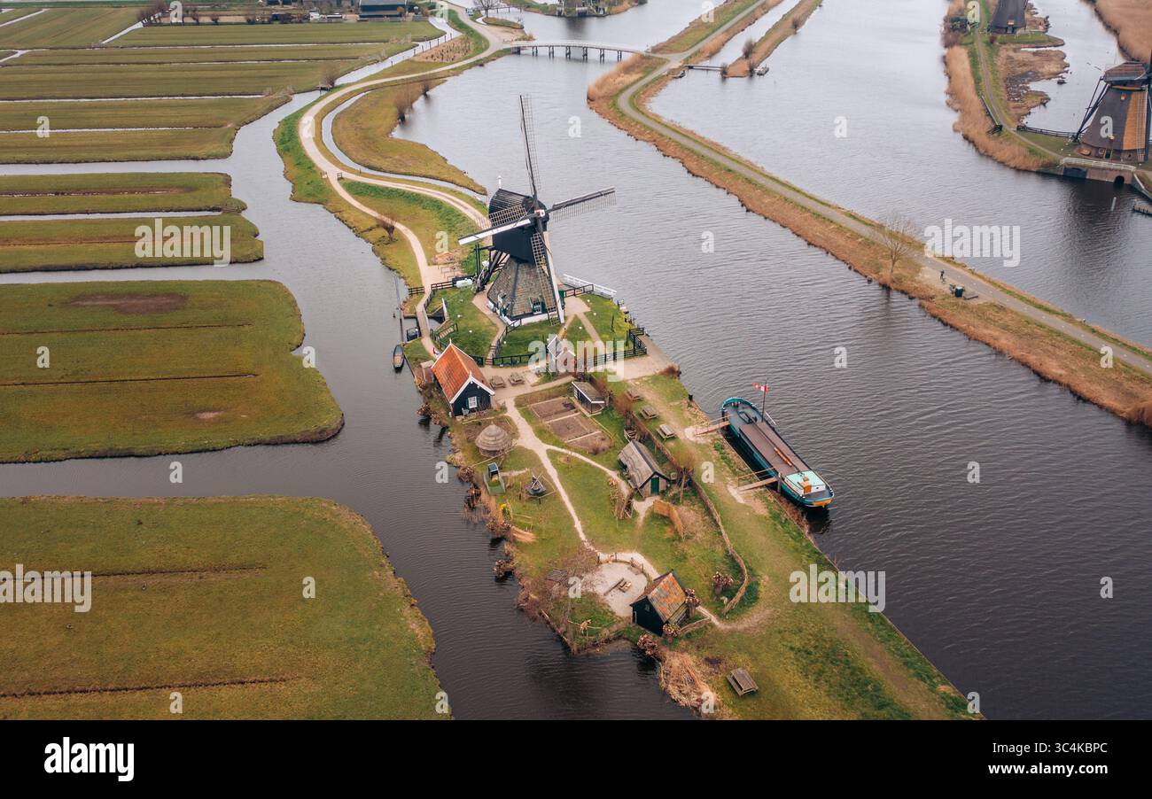 Veduta aerea di un classico mulino a vento olandese in piedi orgogliosamente tra una rete di canali e campi, Kinderdijk, Olanda meridionale, Paesi Bassi. Foto Stock