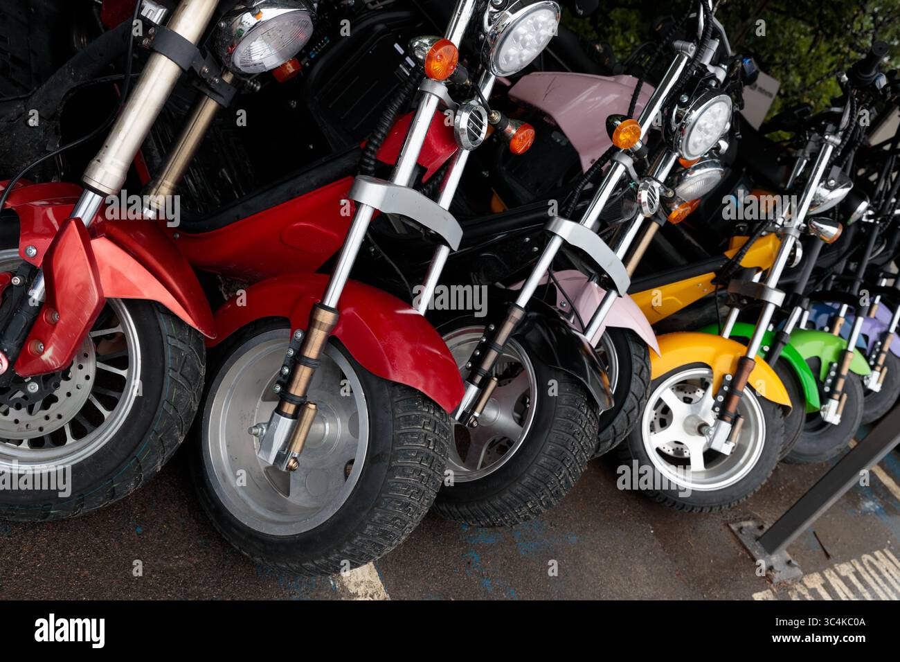 Collezione colorata di motociclette compatte in fila con vari design, stili e colori vivaci per appassionati e motociclisti Foto Stock