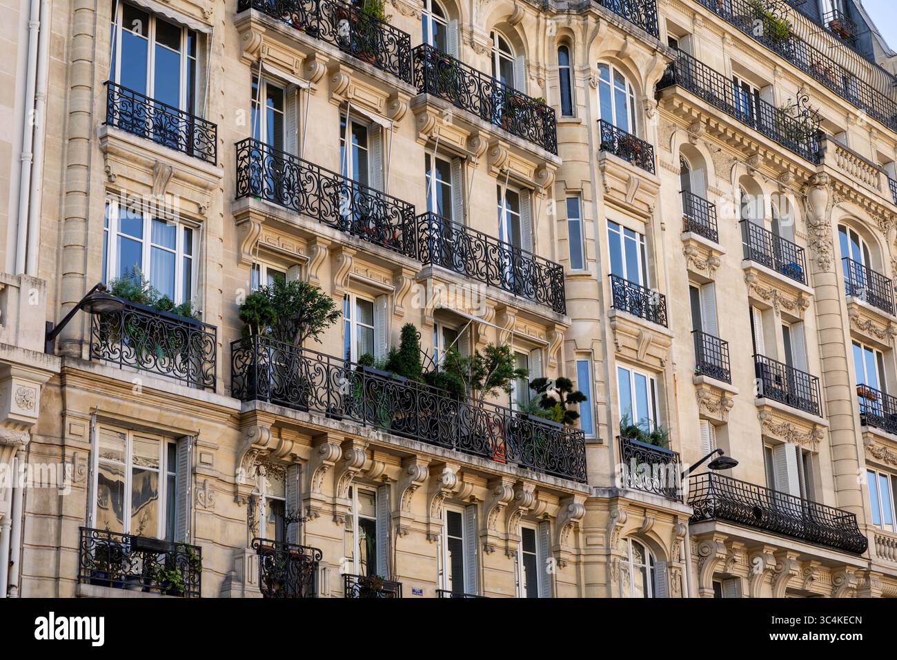 Elegante facciata parigina dell'edificio di appartamenti, con balconi ornati in ferro battuto e finestre illuminate dal sole. Ideale per viaggi, immobili e architetti Foto Stock