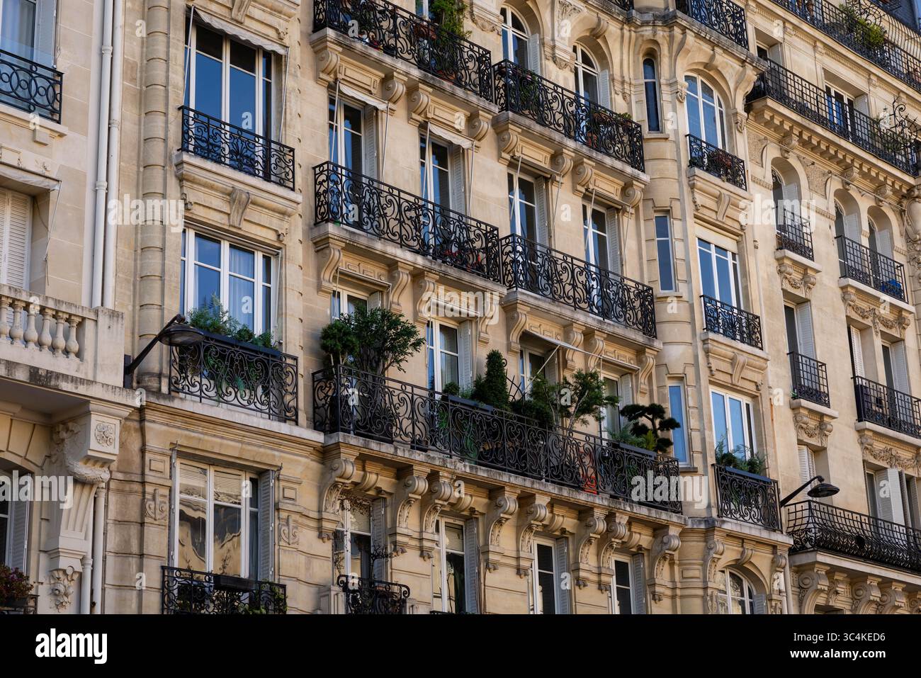 Elegante facciata parigina dell'edificio di appartamenti, con balconi ornati in ferro battuto e grandi finestre. Atmosfera calda e invitante; ideale per i viaggi, vero e proprio Foto Stock