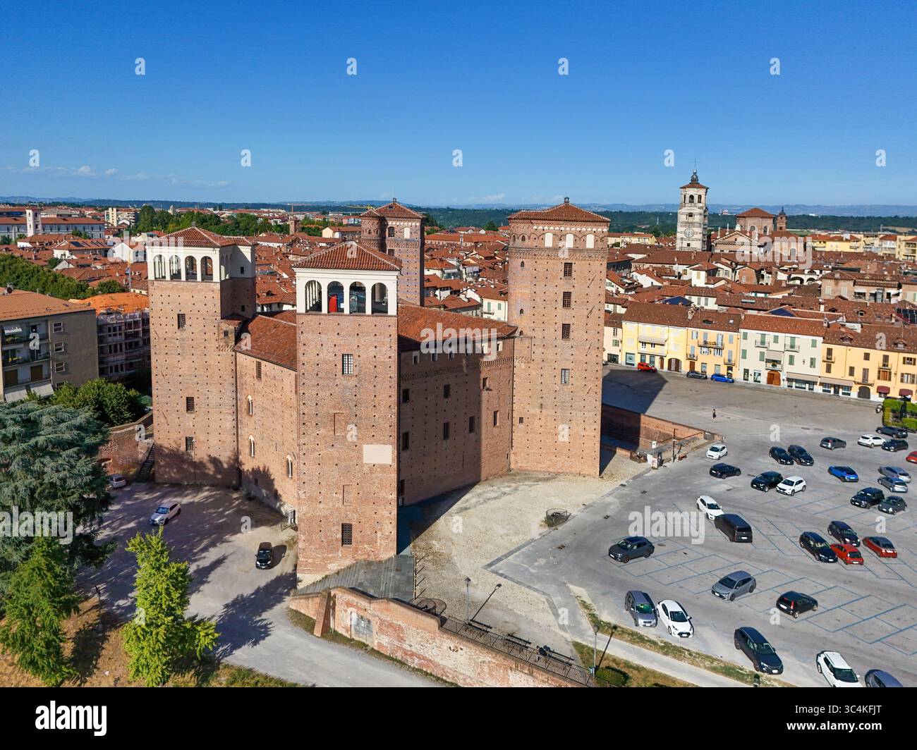 La vista aerea dell'imponente Castello degli Acaja, una suggestiva fortezza in mattoni rossi, domina il paesaggio della città sotto un cielo azzurro, Piazza Castello, Fossano, Piemonte, Italia. Foto Stock