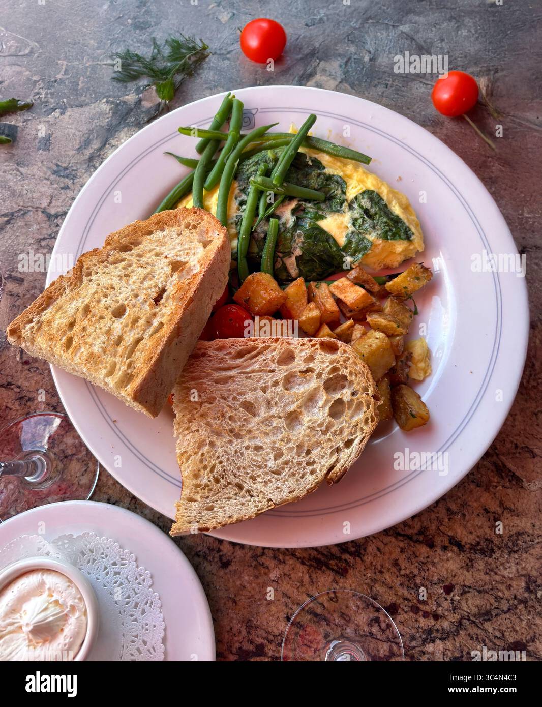 Colazione con pane tostato, omelette con spinaci e fagioli e patate fritte su un piatto bianco. Vista dall'alto Foto Stock