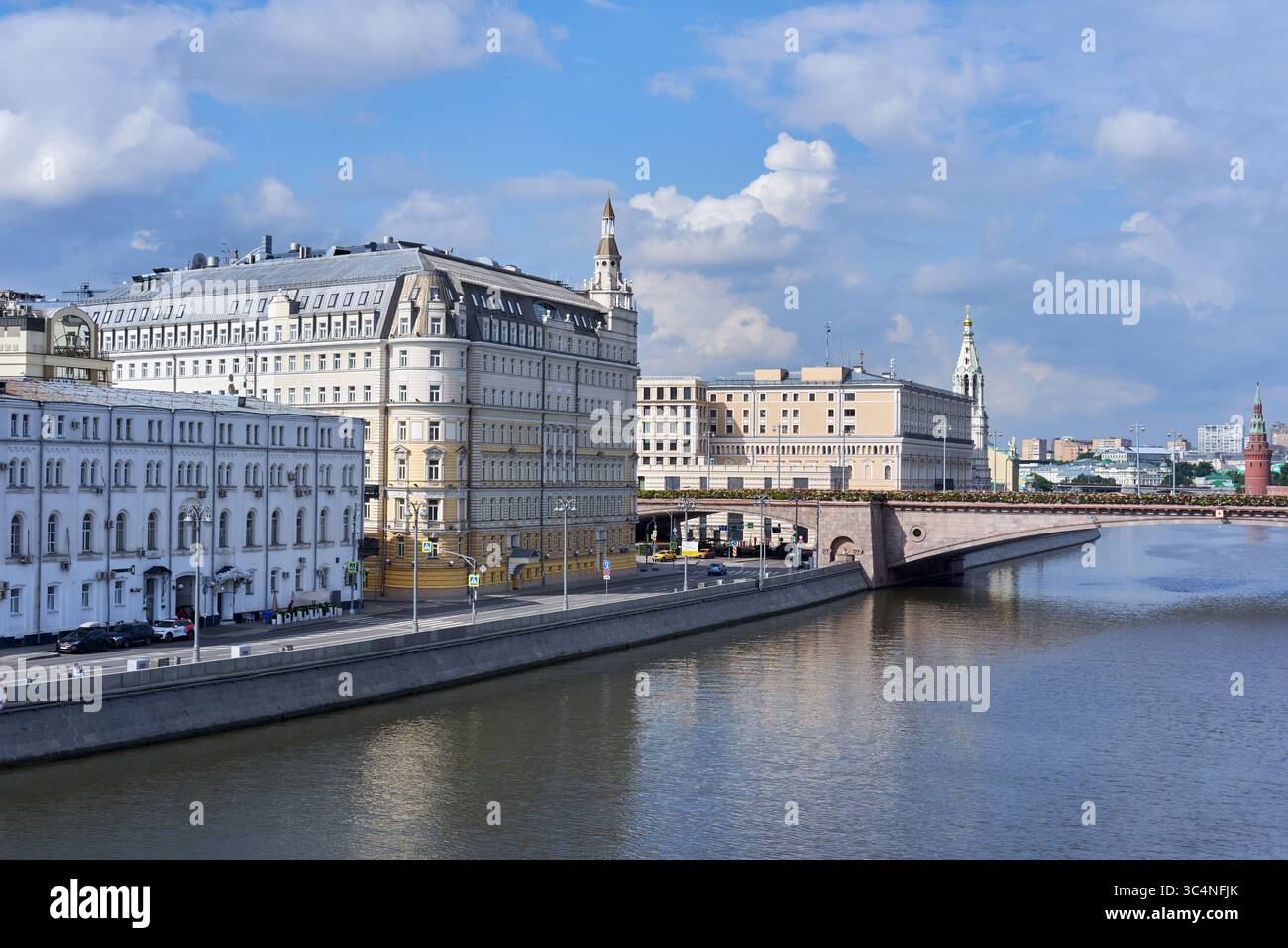 Eleganti edifici storici fiancheggiano l'argine del fiume Moskva accanto al ponte Bolshoy Moskvoretsky in una giornata di sole Foto Stock