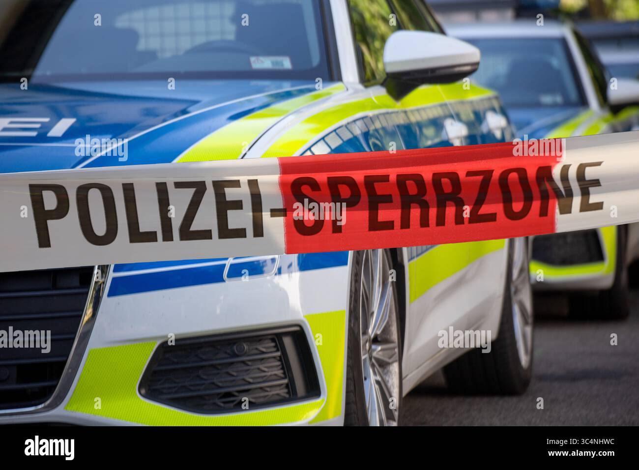 (Fotomontaggio) immagine simbolica dell'operazione di polizia: Nastro barriera di polizia davanti ai veicoli di emergenza Foto Stock (Fotomontaggio) immagine simbolica dell'operazione di polizia: Nastro barriera di polizia davanti ai veicoli di emergenza Foto Stock