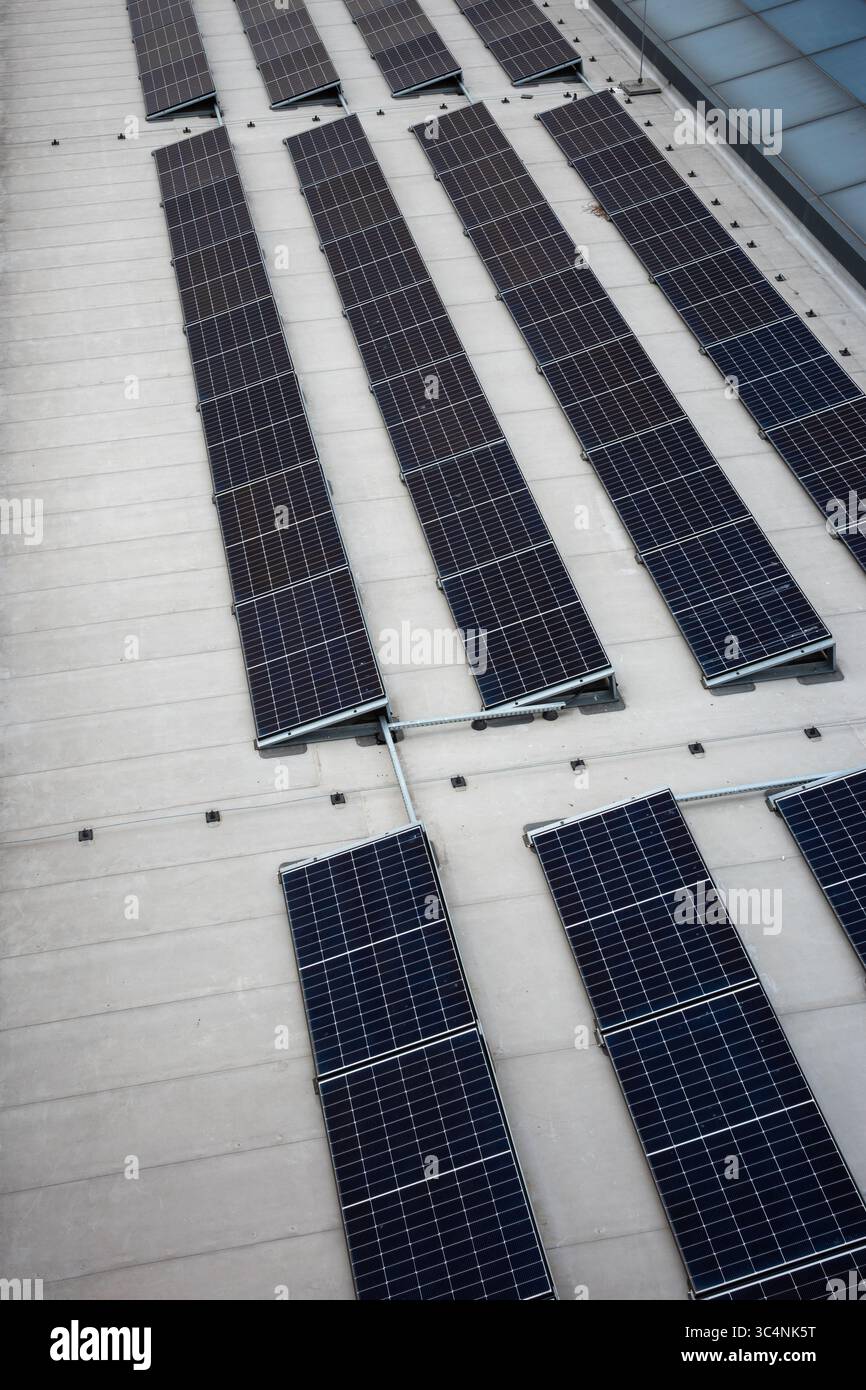 Set di pannelli solari sulla sommità del tetto in cemento di un edificio moderno. Le fonti di energia fotovoltaica aiutano ad aumentare la domanda di energia Foto Stock