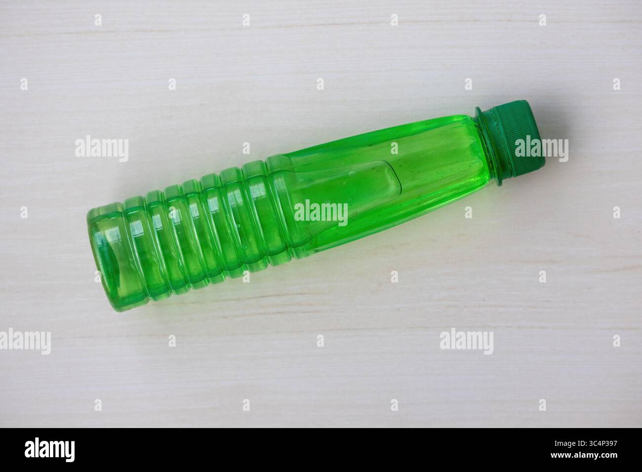 Bottiglia verde di acqua di kewra (keora jol) su una superficie di legno naturale. Ingrediente essenziale per la cucina dell'Asia meridionale, dessert e bevande. Foto Stock