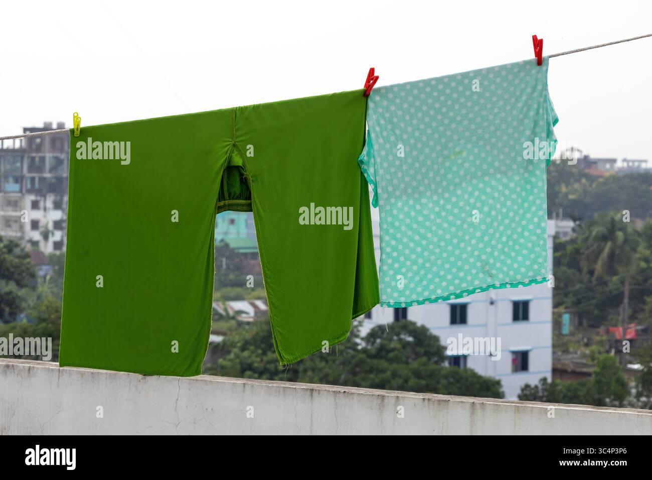 il palazzo delle salwar verdi da donna e i tetti a pois turchesi si asciugano su una linea di tegole sul tetto con spille. Giorno di bucato all'aperto con una vivace estate Foto Stock