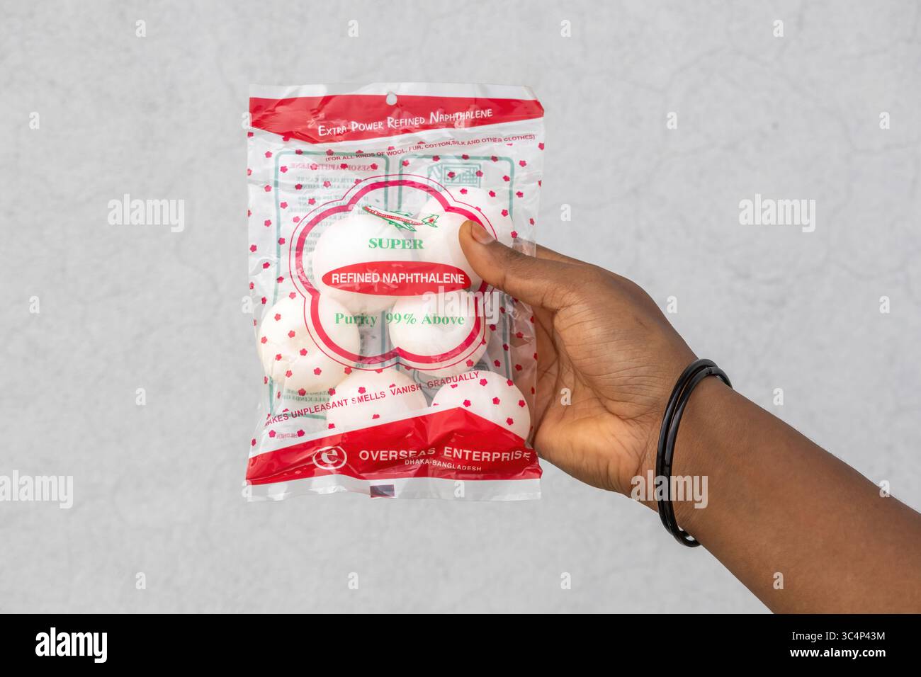 Mano che tiene il nuovo pacchetto di naftalene, noto anche come catrame bianco, palle di neve o catrame di canfora. Fiocchi di antimite freschi per il controllo dei parassiti, una falena di albocarburo Foto Stock